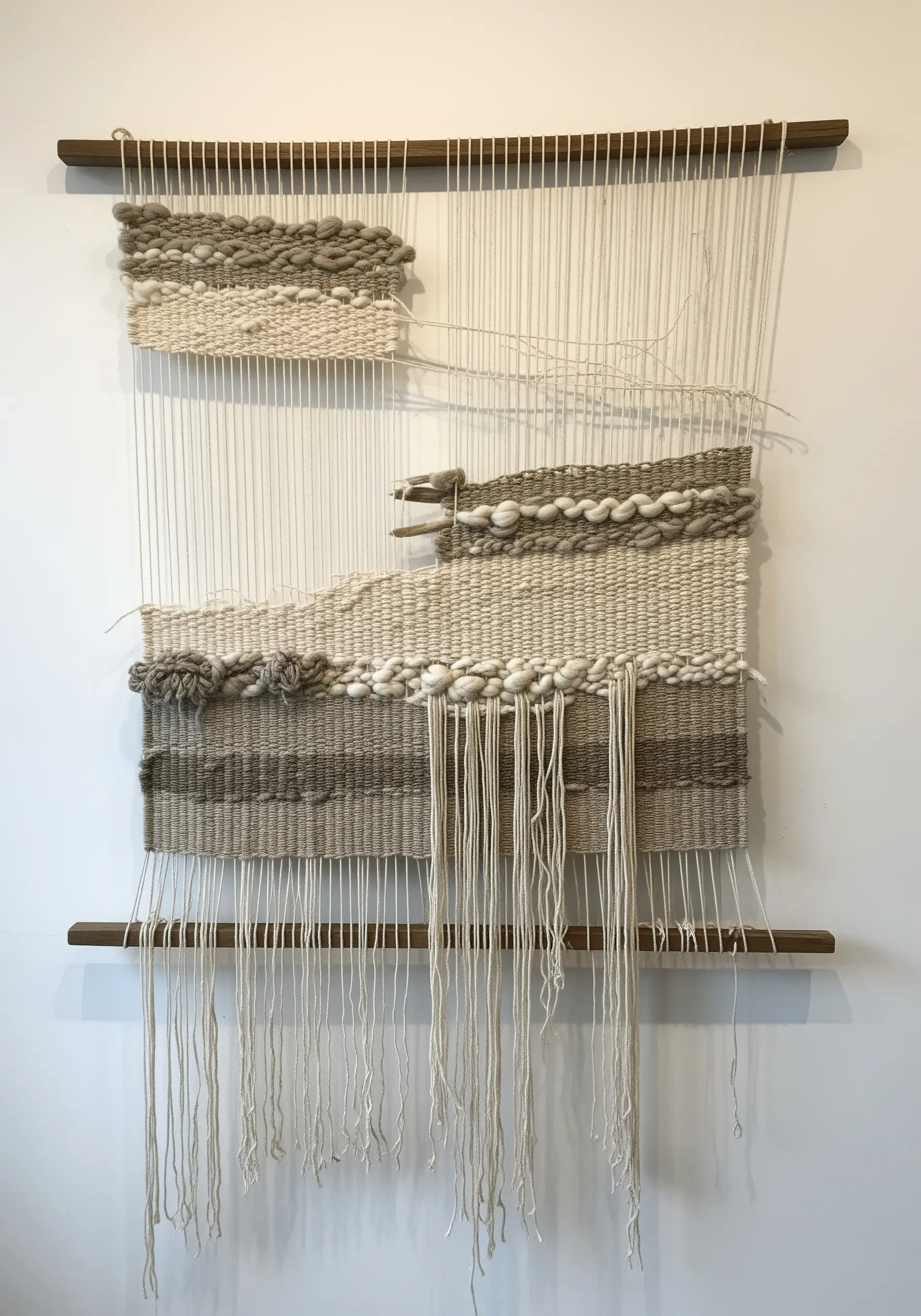 A deconstructed weaving with small, textured neutral panels on a largely exposed warp frame.