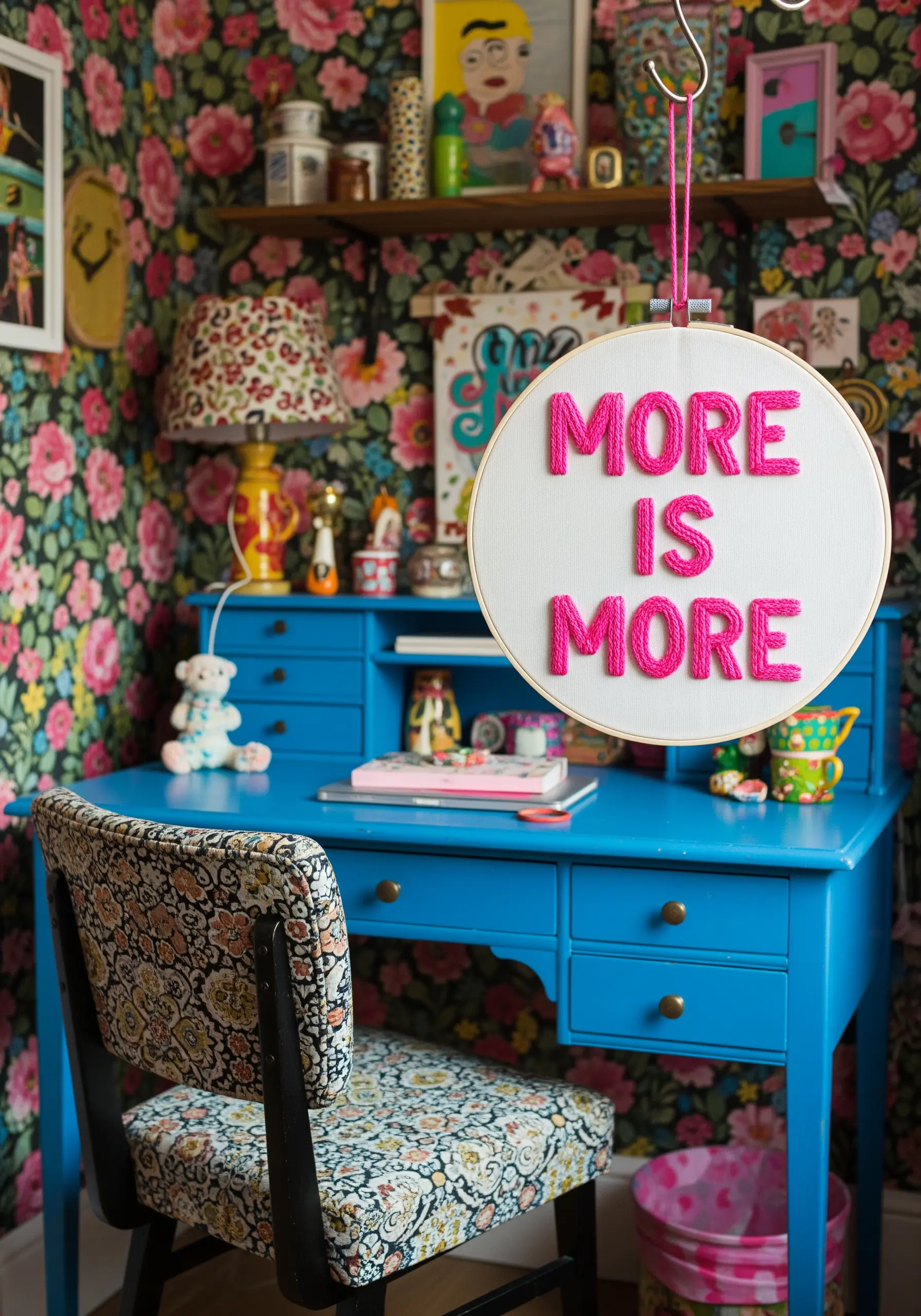 The phrase 'More is More' in bold pink punch needle embroidery in a hoop.