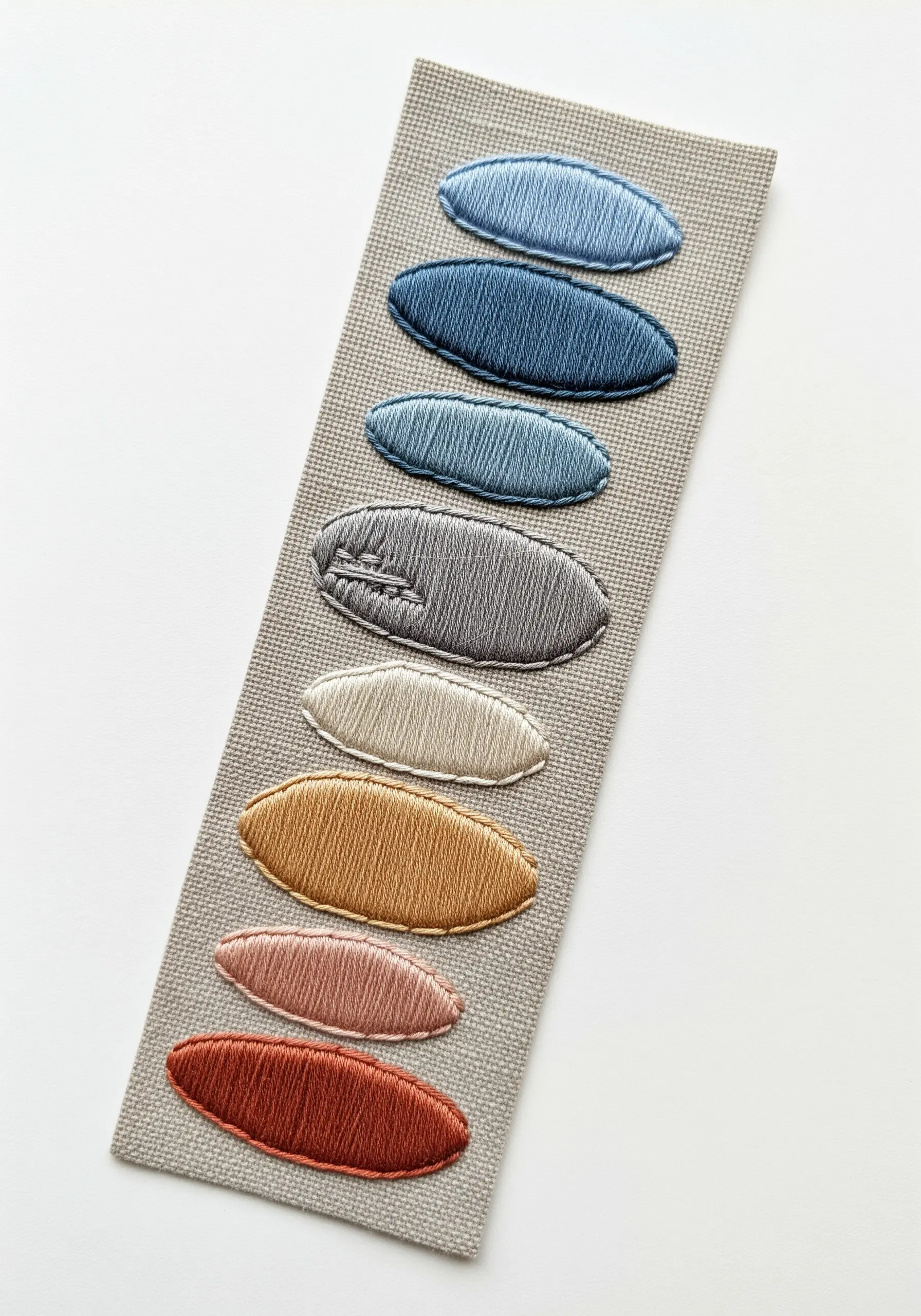 An embroidered color study showing eight ovals in a gradient from blue to terracotta.