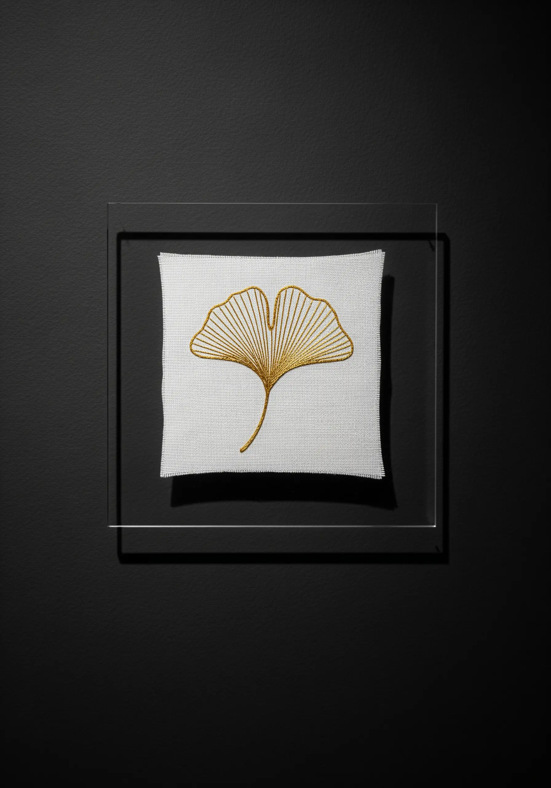 Gold metallic thread embroidery of a ginkgo leaf in a modern floating acrylic frame.