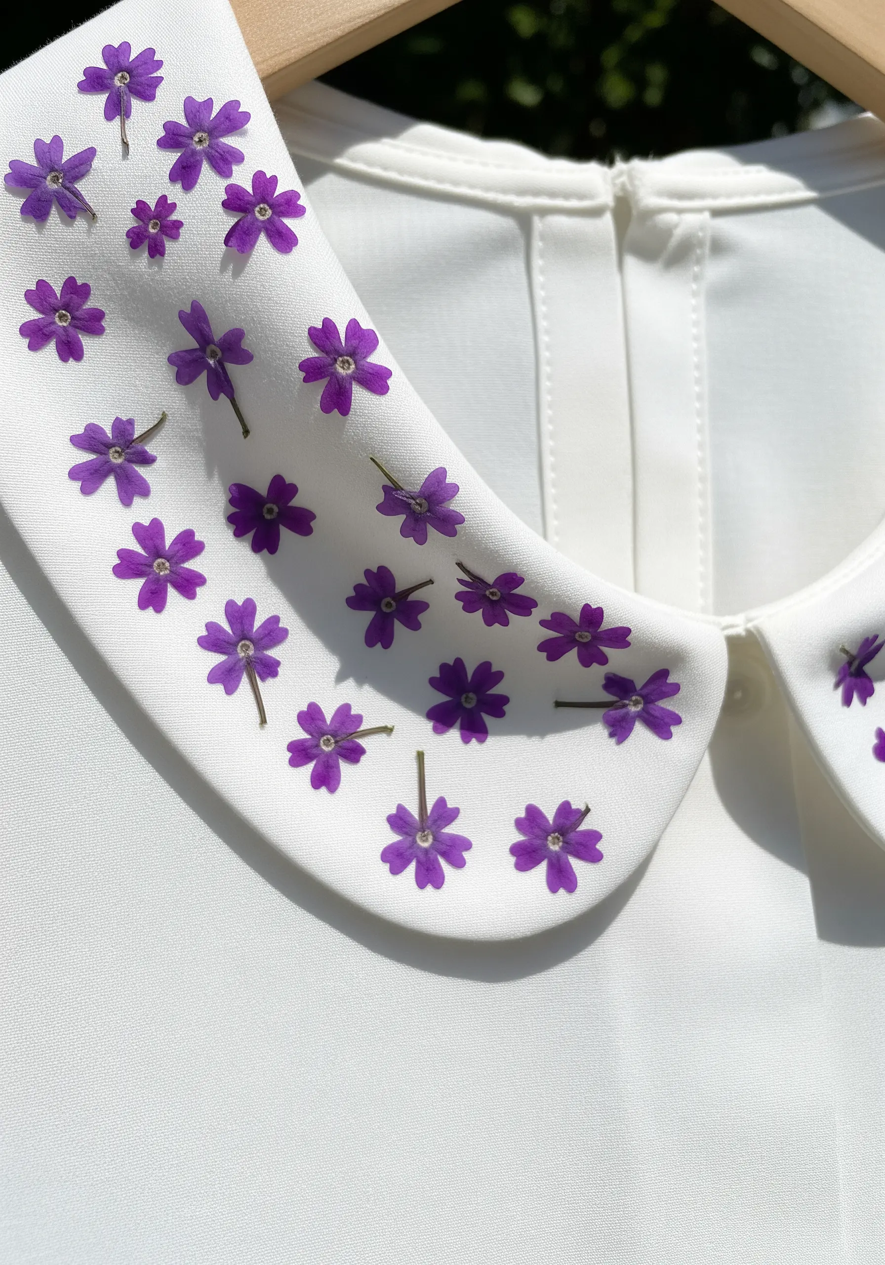A white shirt collar decorated with small, scattered pressed purple verbena flowers.