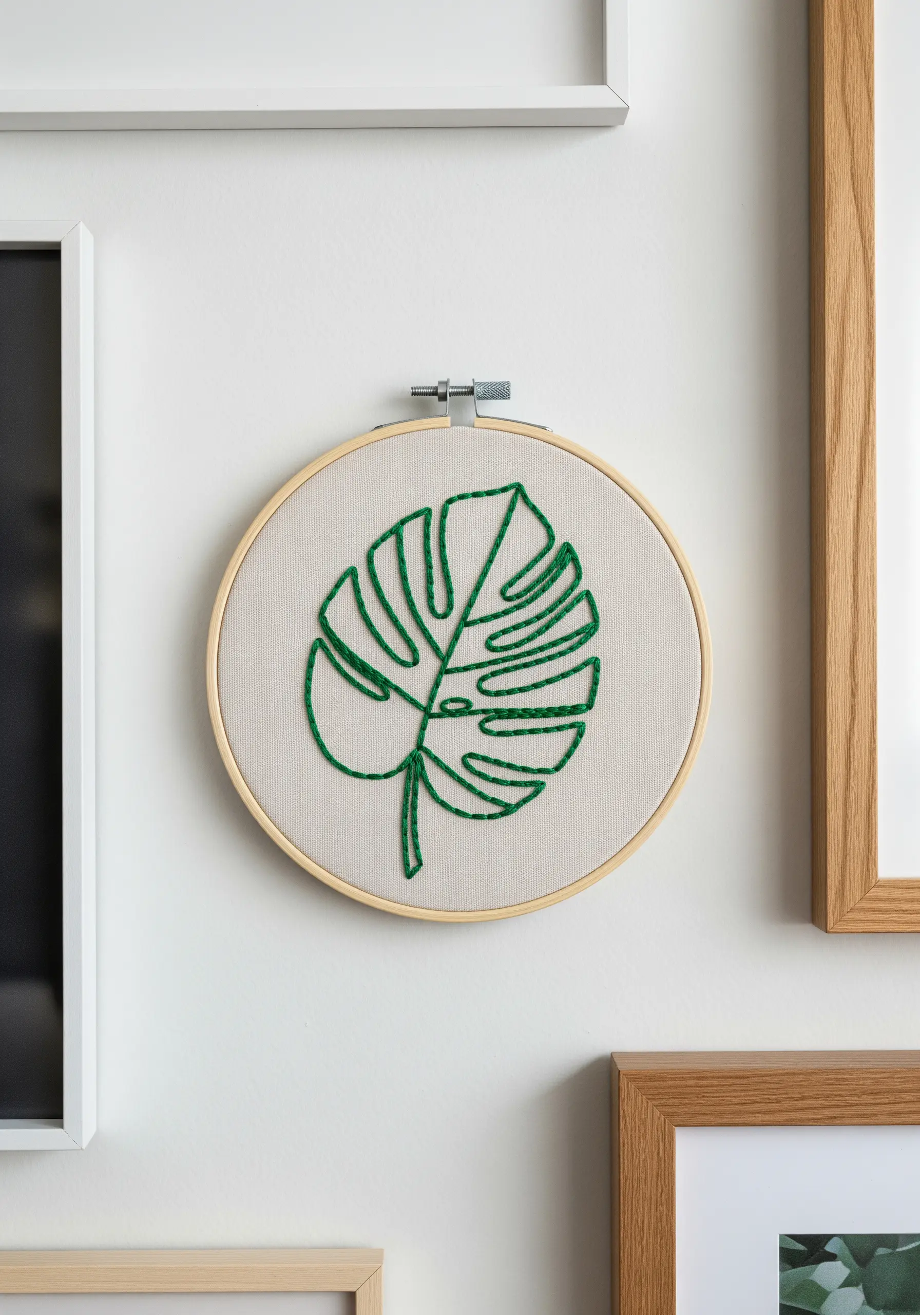 An embroidery hoop with a bold, green line-art monstera leaf.
