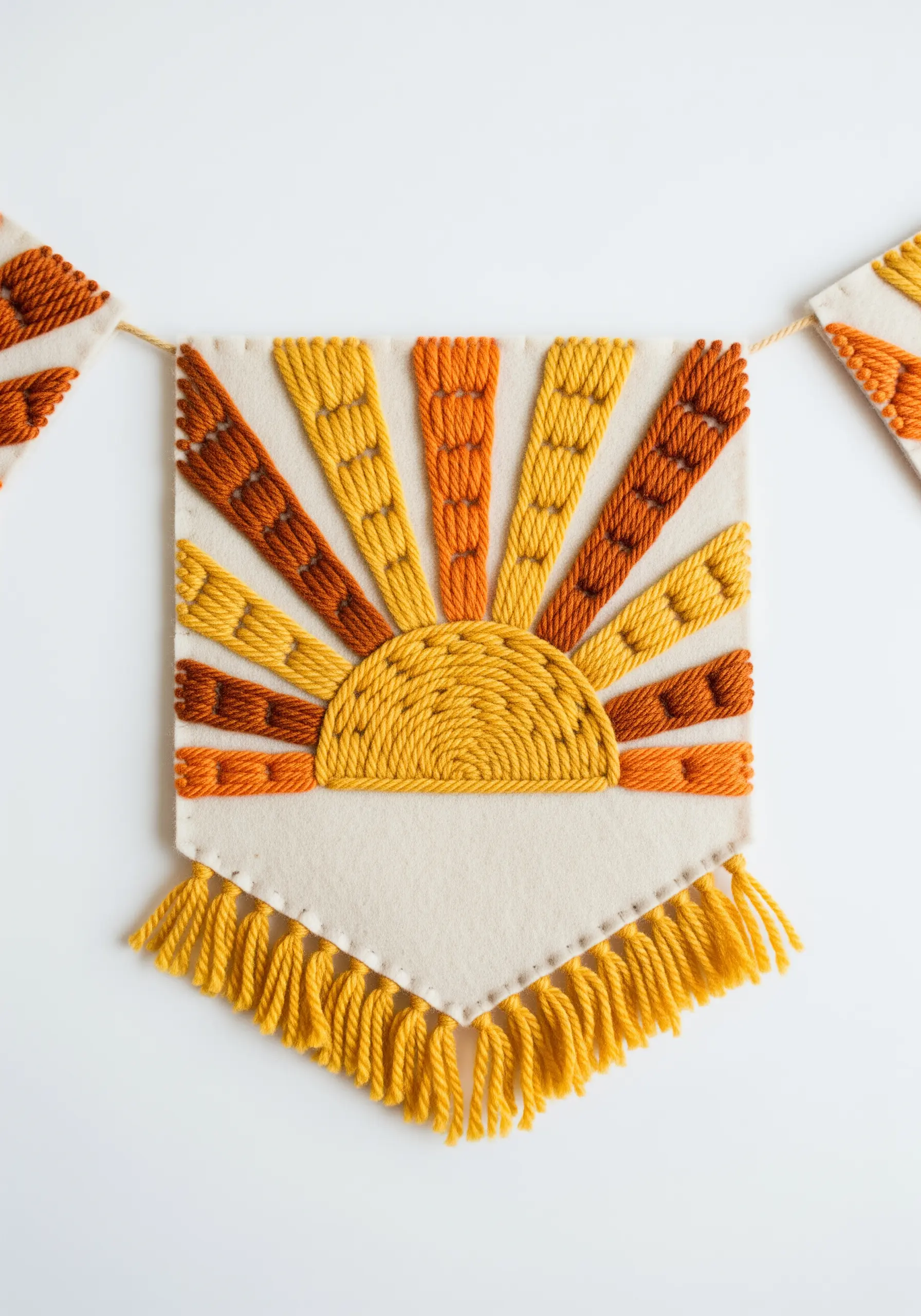 Embroidered felt banner with a sunburst motif stitched in yellow and orange yarn.