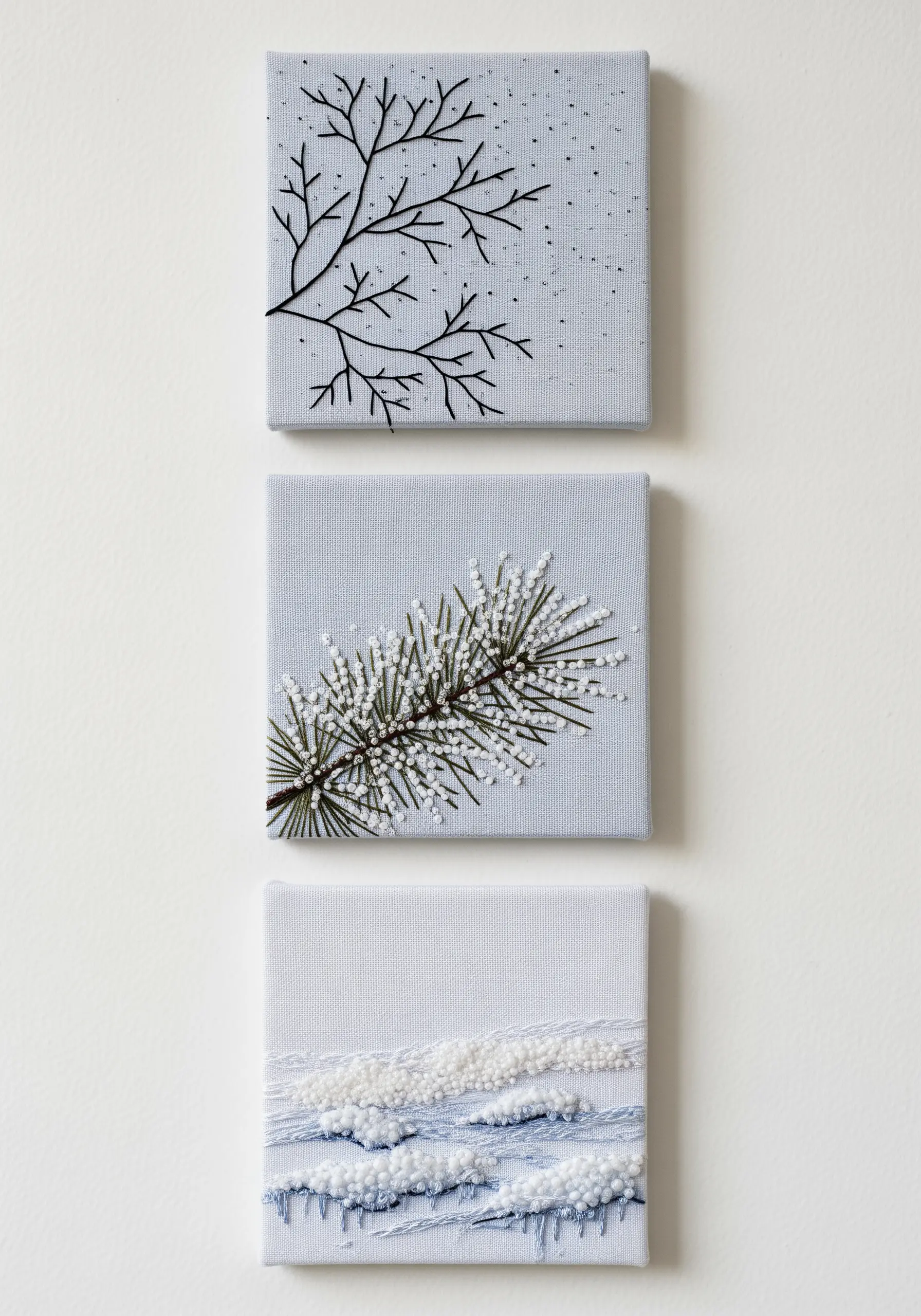 A triptych of small canvas embroideries showing minimalist winter scenes.