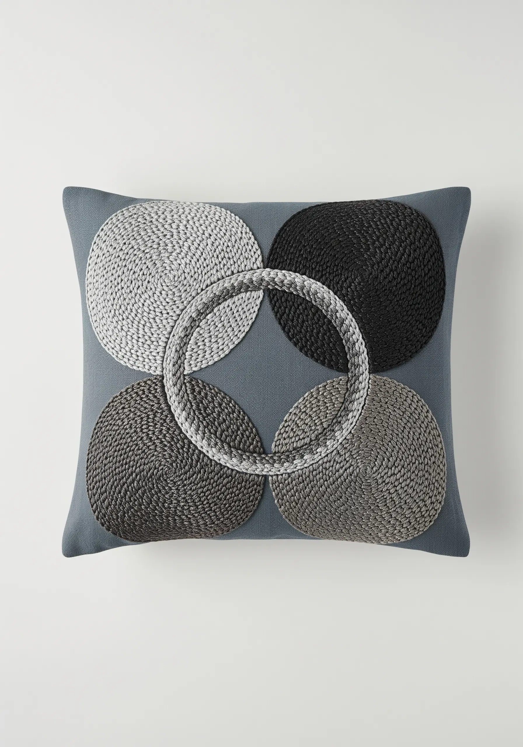 Four overlapping circles in a grayscale gradient using a textured, couched stitch.