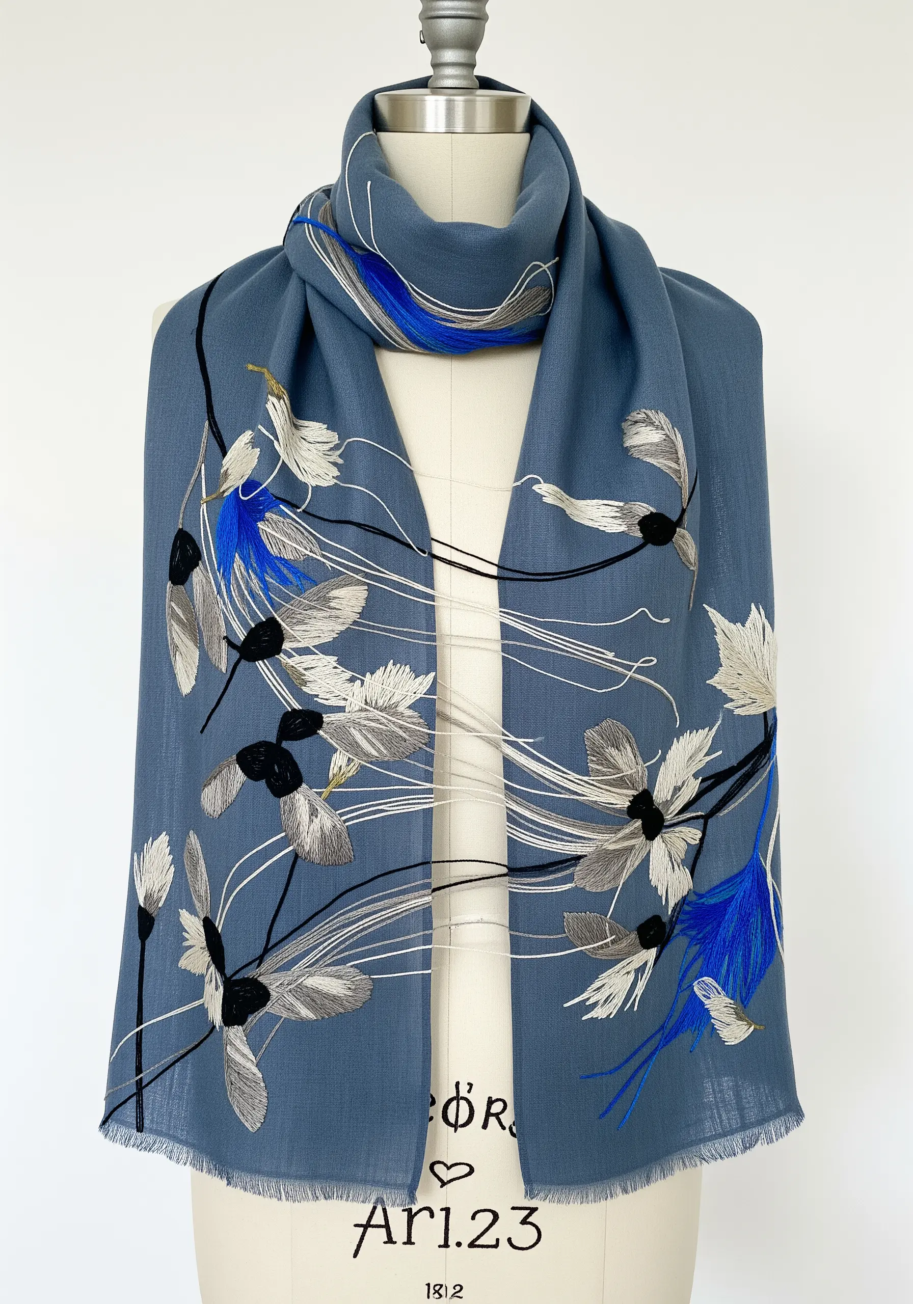 Abstract embroidery of seed pods and leaves with long, loose threads on a blue scarf.