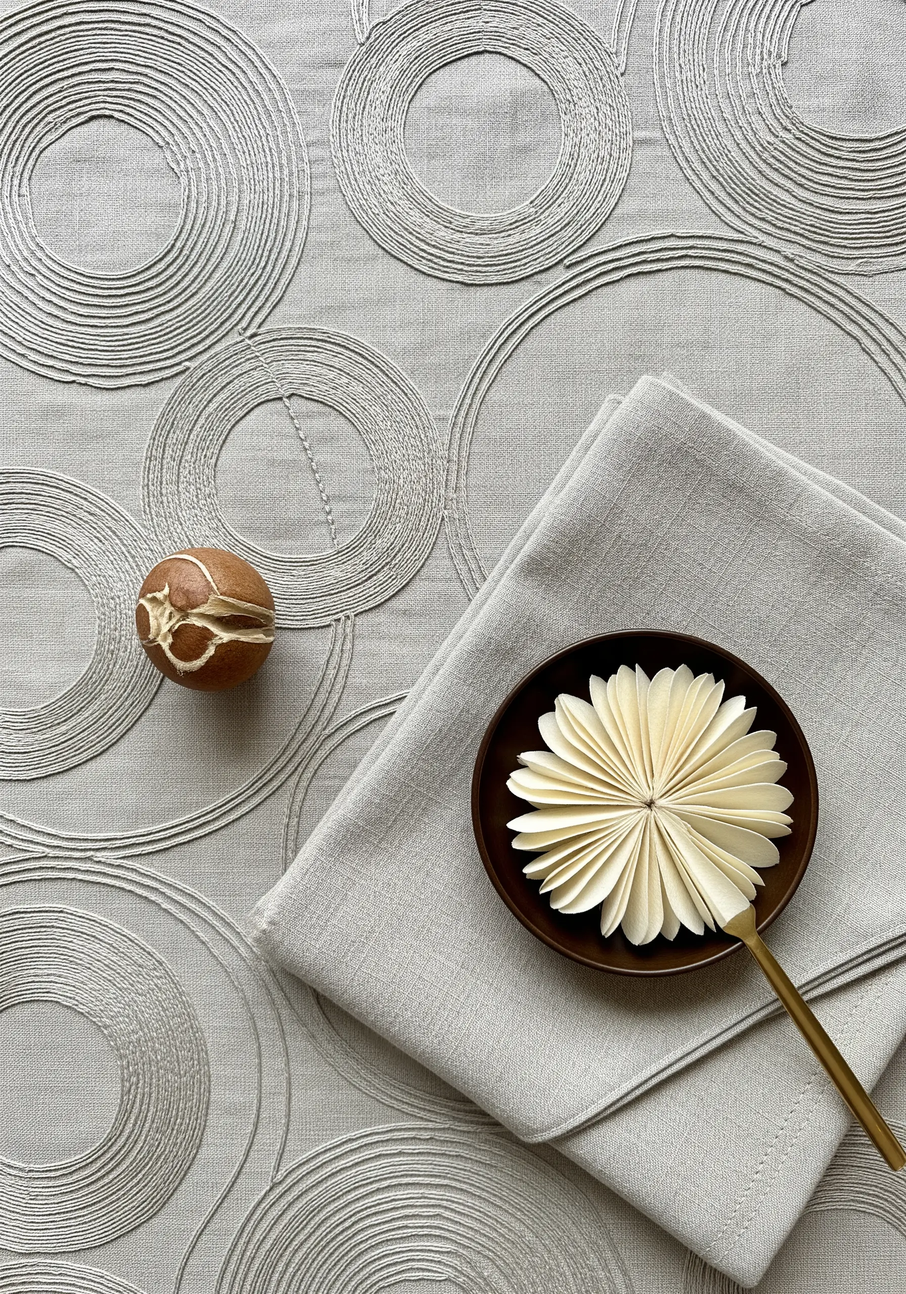 Concentric circles stitched in a light grey thread on a slightly darker grey linen fabric.
