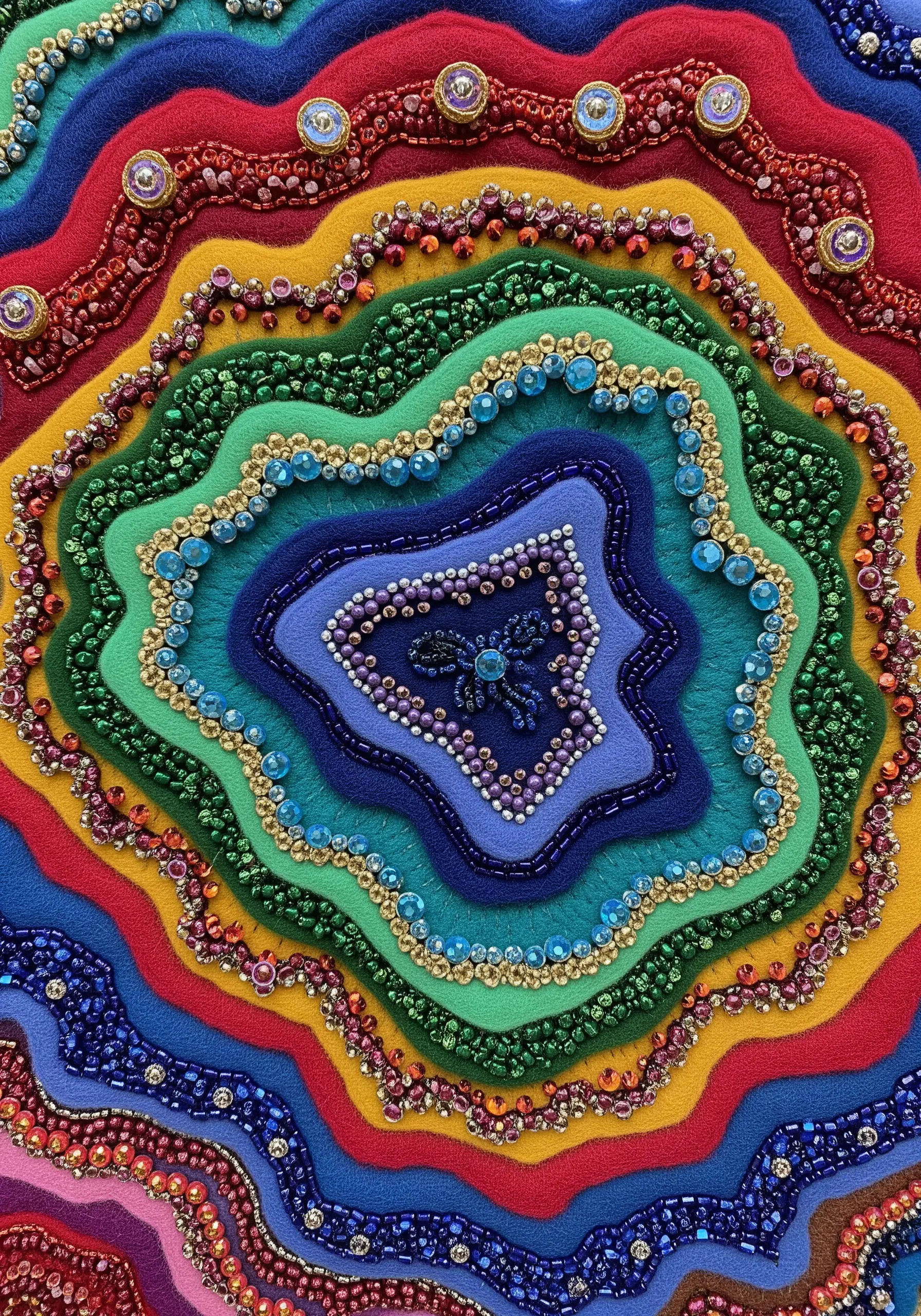 Colorful layered felt in organic shapes, embellished with beads to look like a geode.