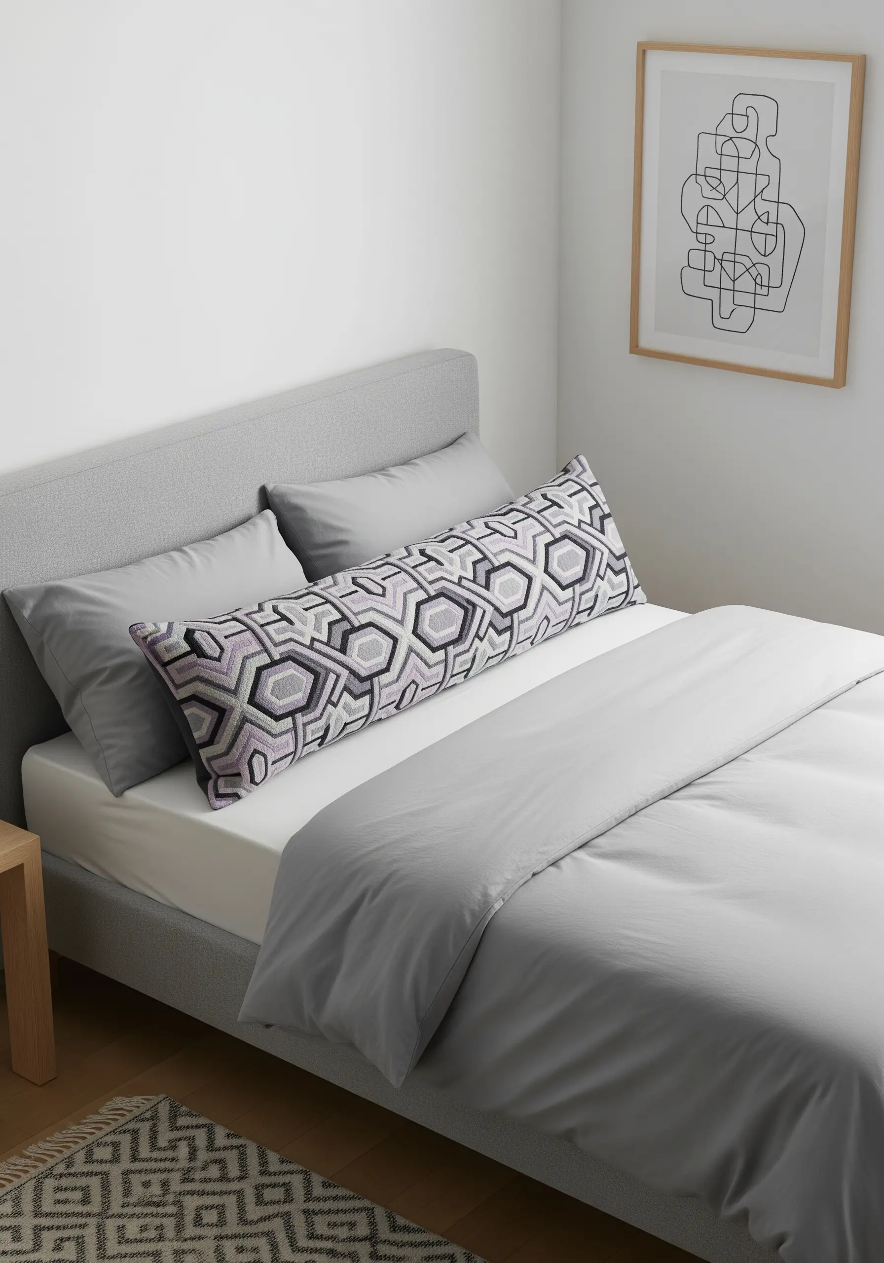 A long geometric-patterned pillow with lavender accents on a modern gray bed.