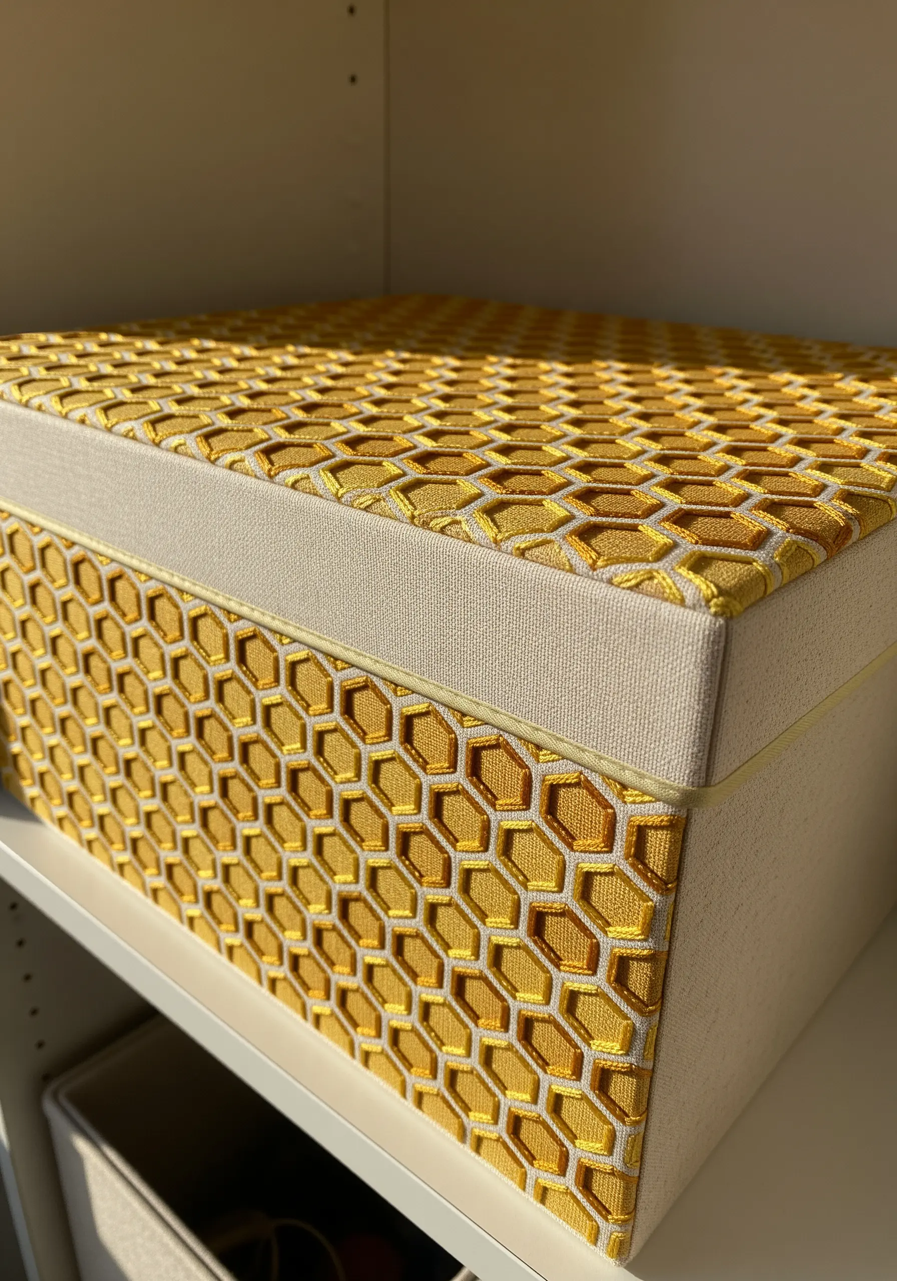A storage box decorated with a precise geometric honeycomb pattern in shades of yellow.