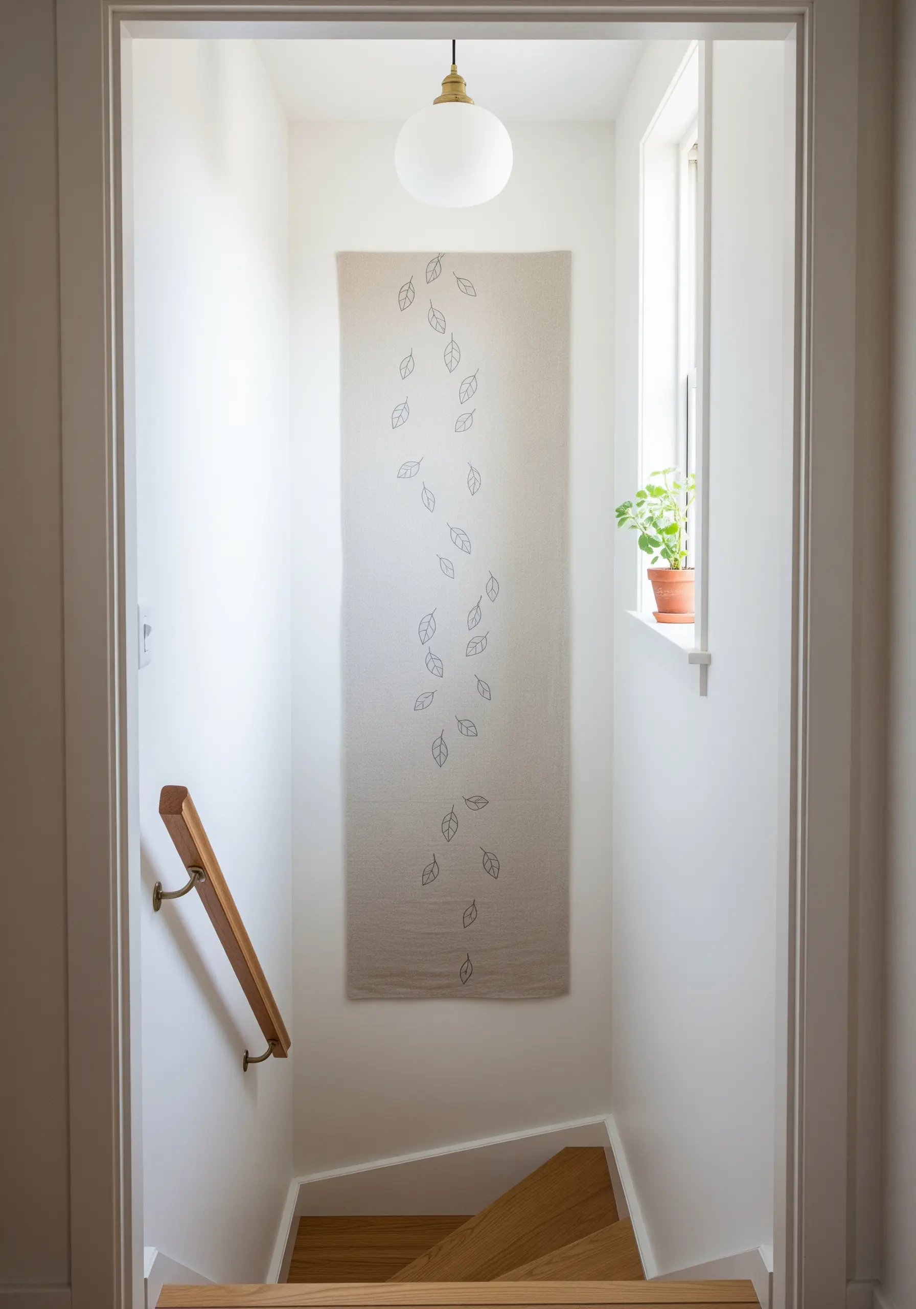 A long, narrow wall hanging in a stairwell featuring a pattern of sparsely embroidered falling leaves.