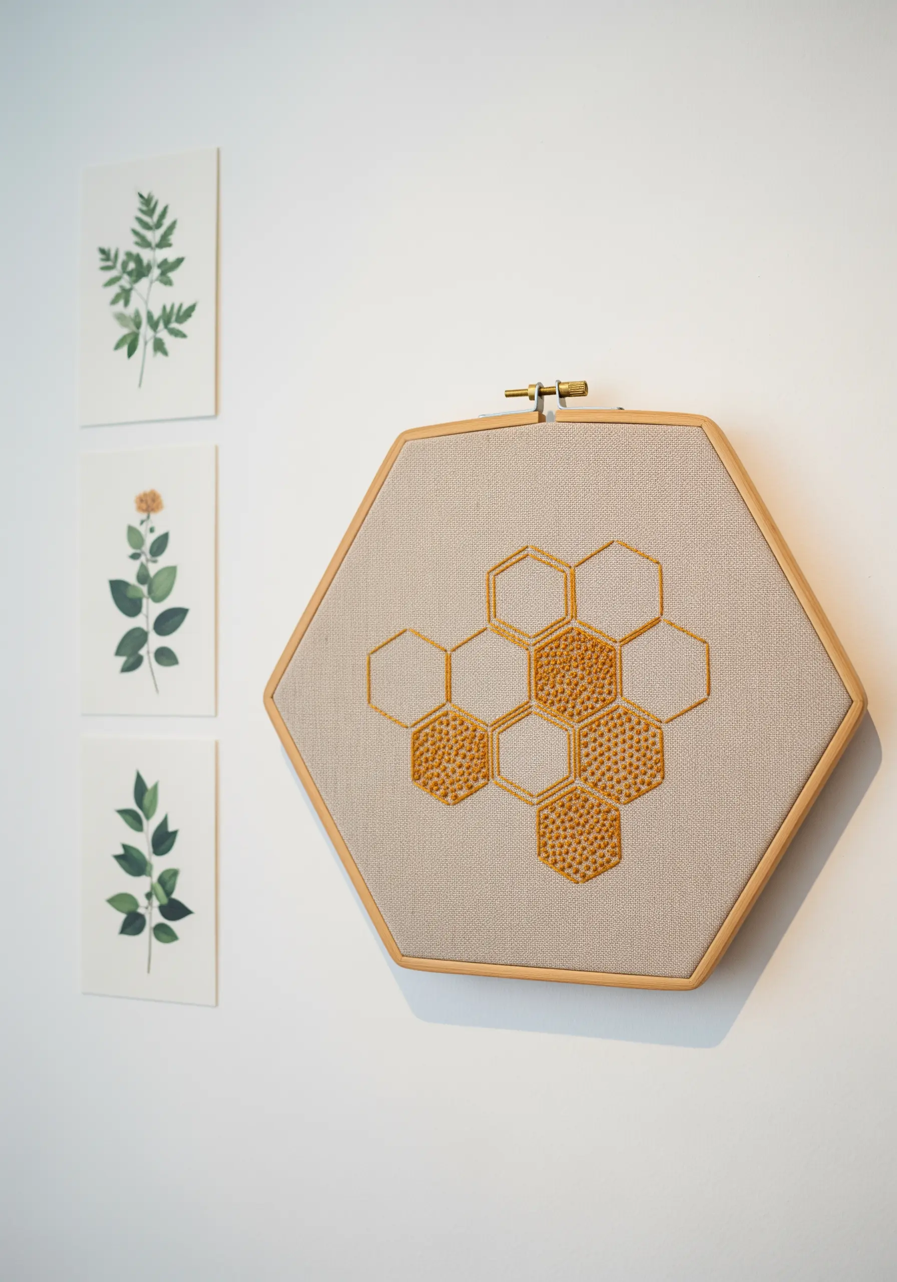 Minimalist honeycomb embroidery in a hexagonal hoop with some cells filled with seed stitch.