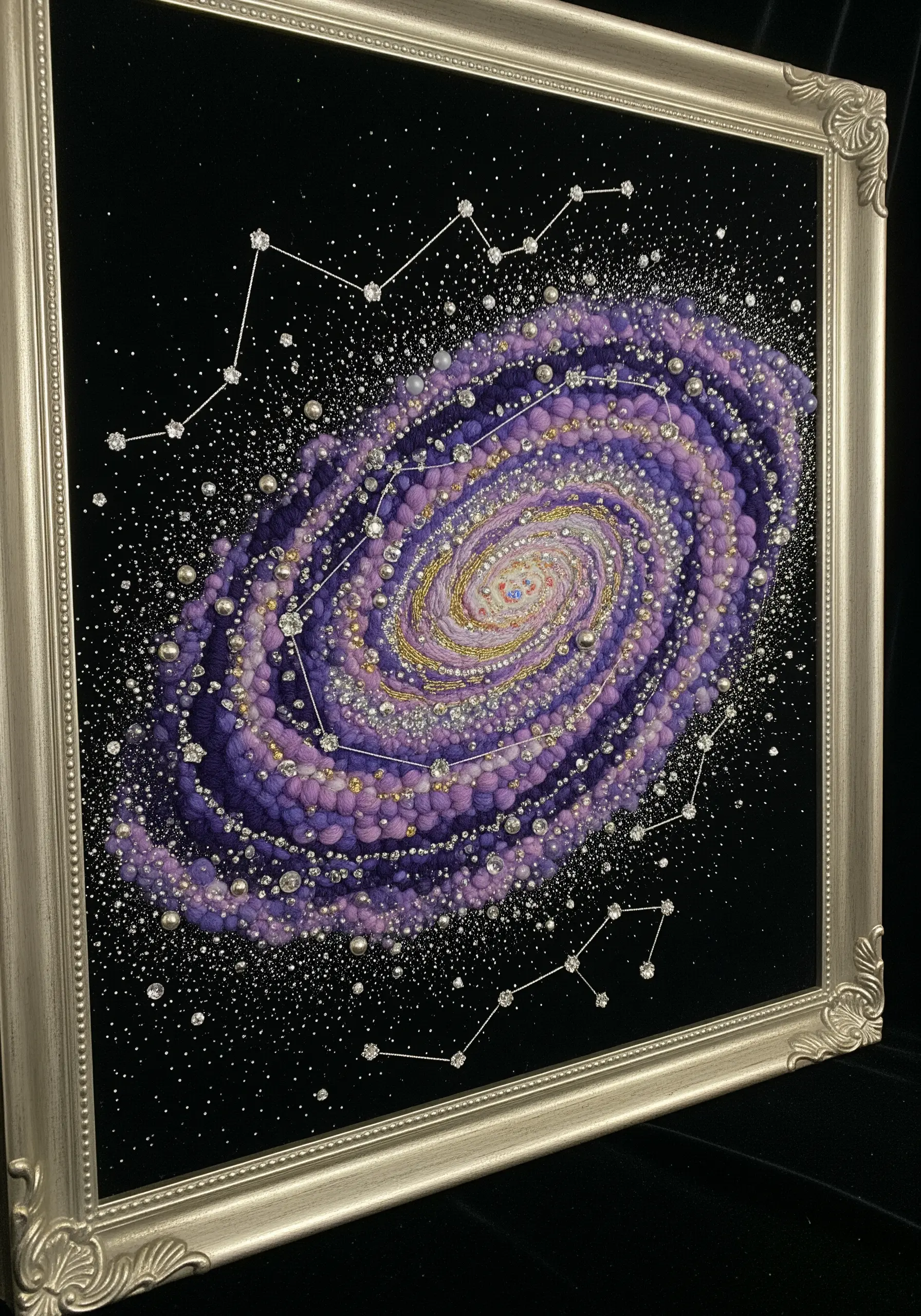 A swirling galaxy made of purple yarn, metallic thread, and silver beads on black velvet.