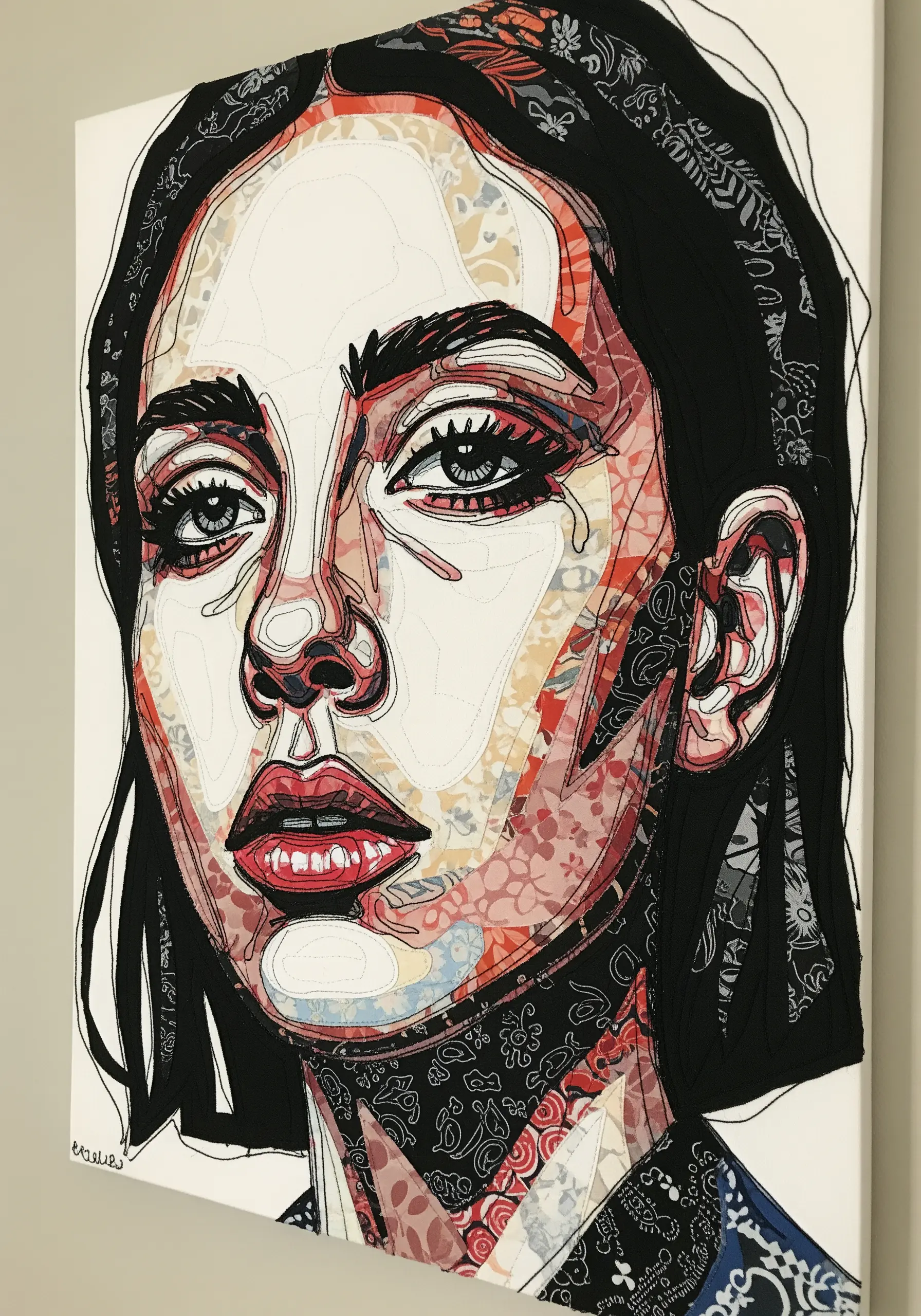 A portrait made from fabric collage, with details outlined in black thread.