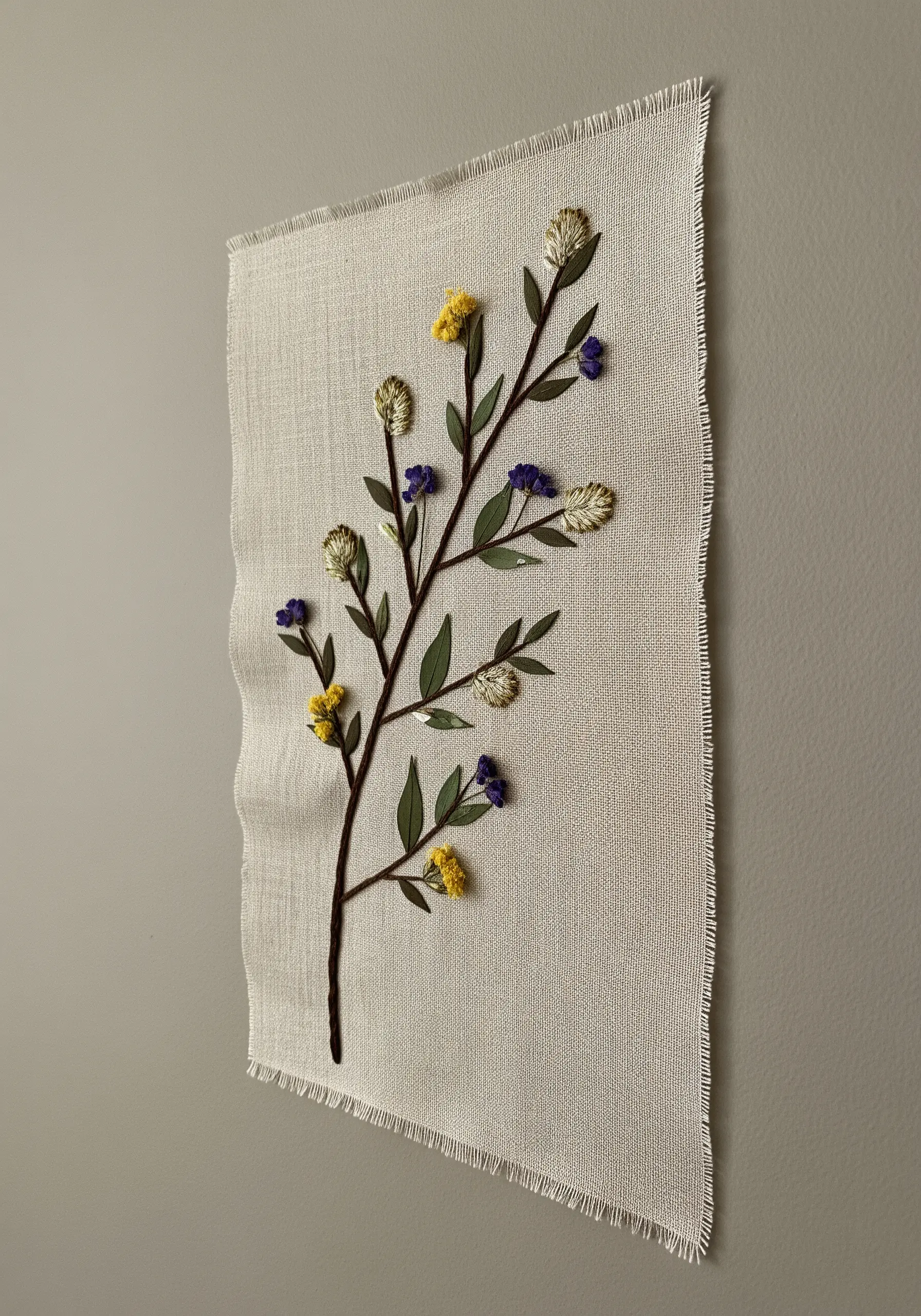 A mixed-media piece with an embroidered branch and real pressed flowers attached.