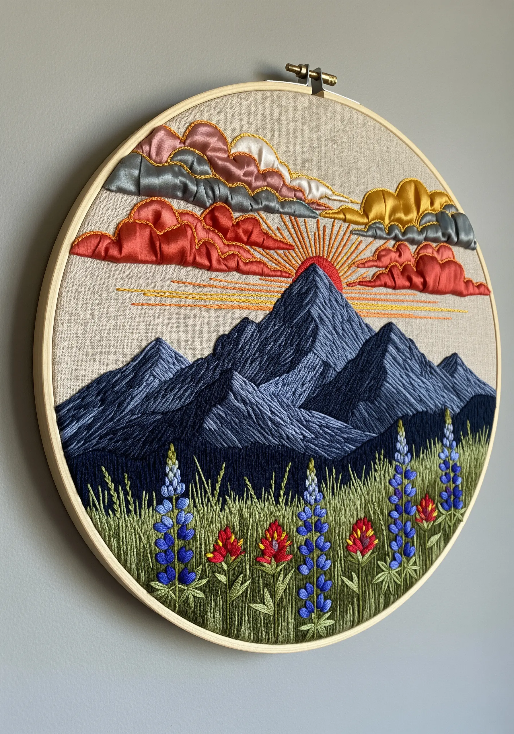 Embroidered mountain landscape with ribbon clouds, thread-painted peaks, and wildflower foreground