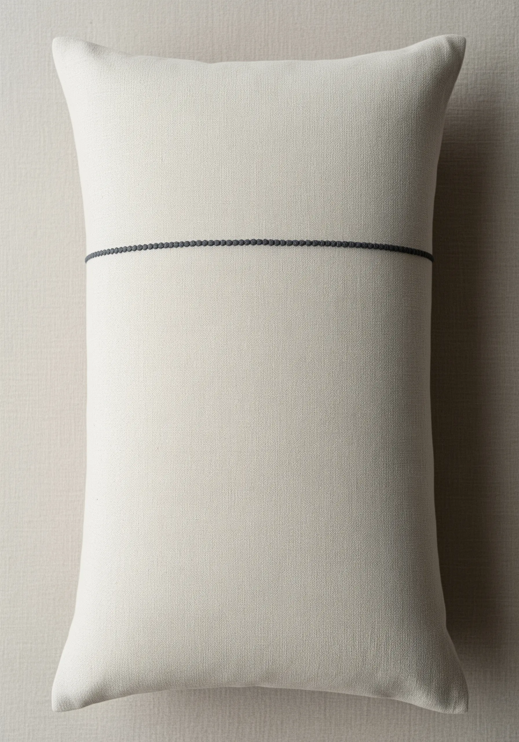 A single horizontal line of decorative black stitches across a rectangular off-white cushion.