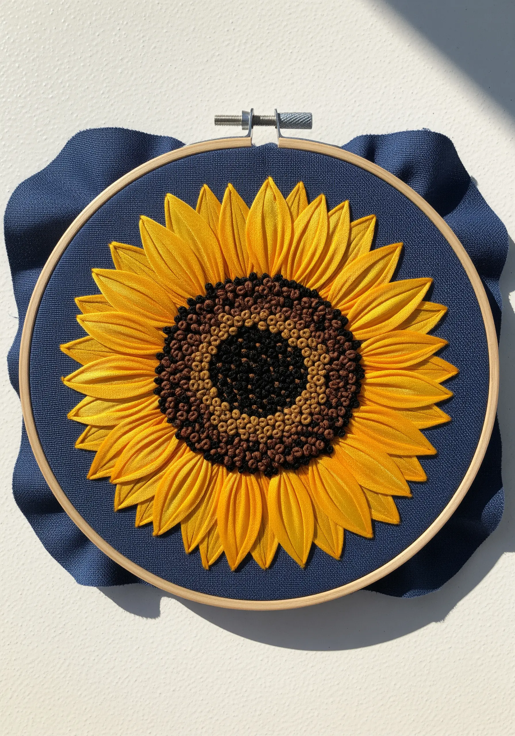 A sunflower embroidered with yellow ribbon for petals and brown French knots for the center.