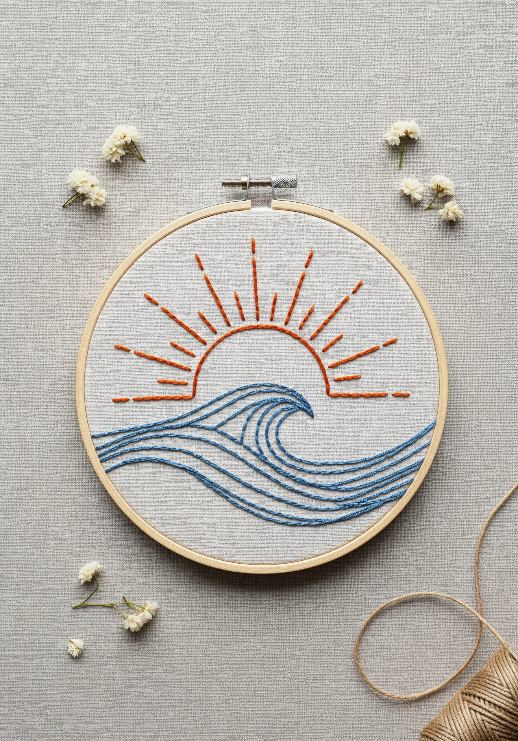 A line art sun and wave motif embroidered in orange and blue thread.