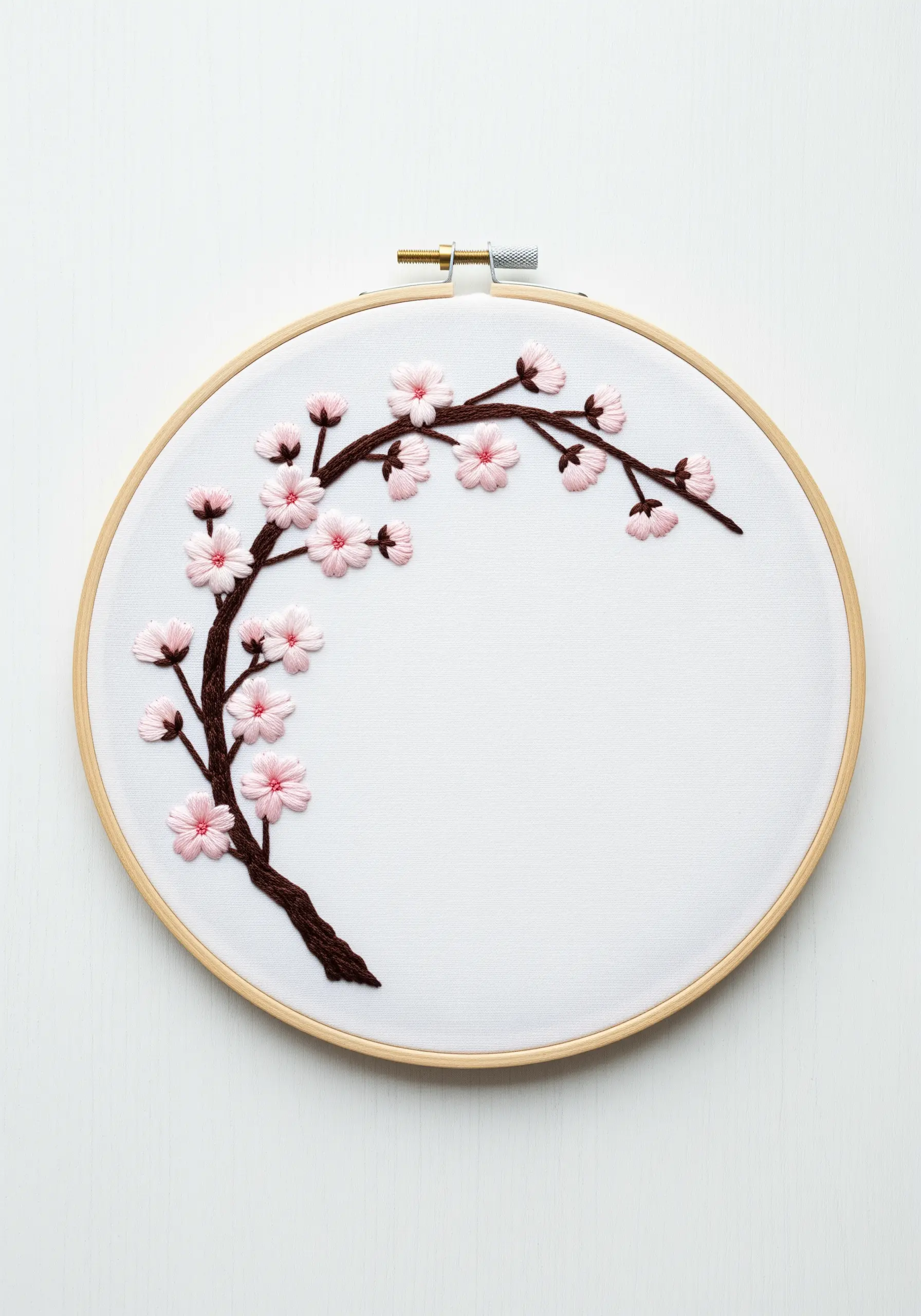 Minimalist cherry blossom branch embroidery on a white fabric background in a hoop.