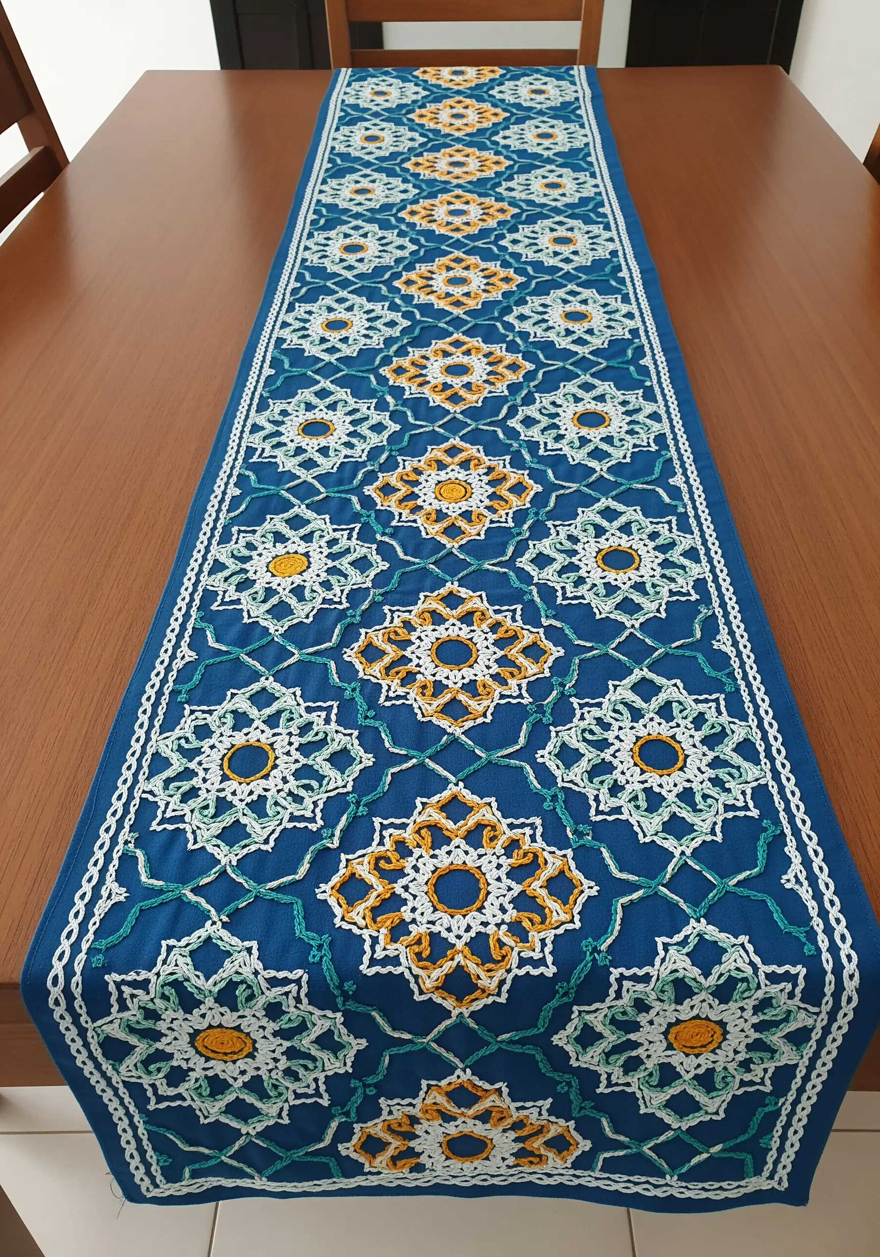 A blue table runner with a repeating geometric pattern inspired by Moroccan tiles.