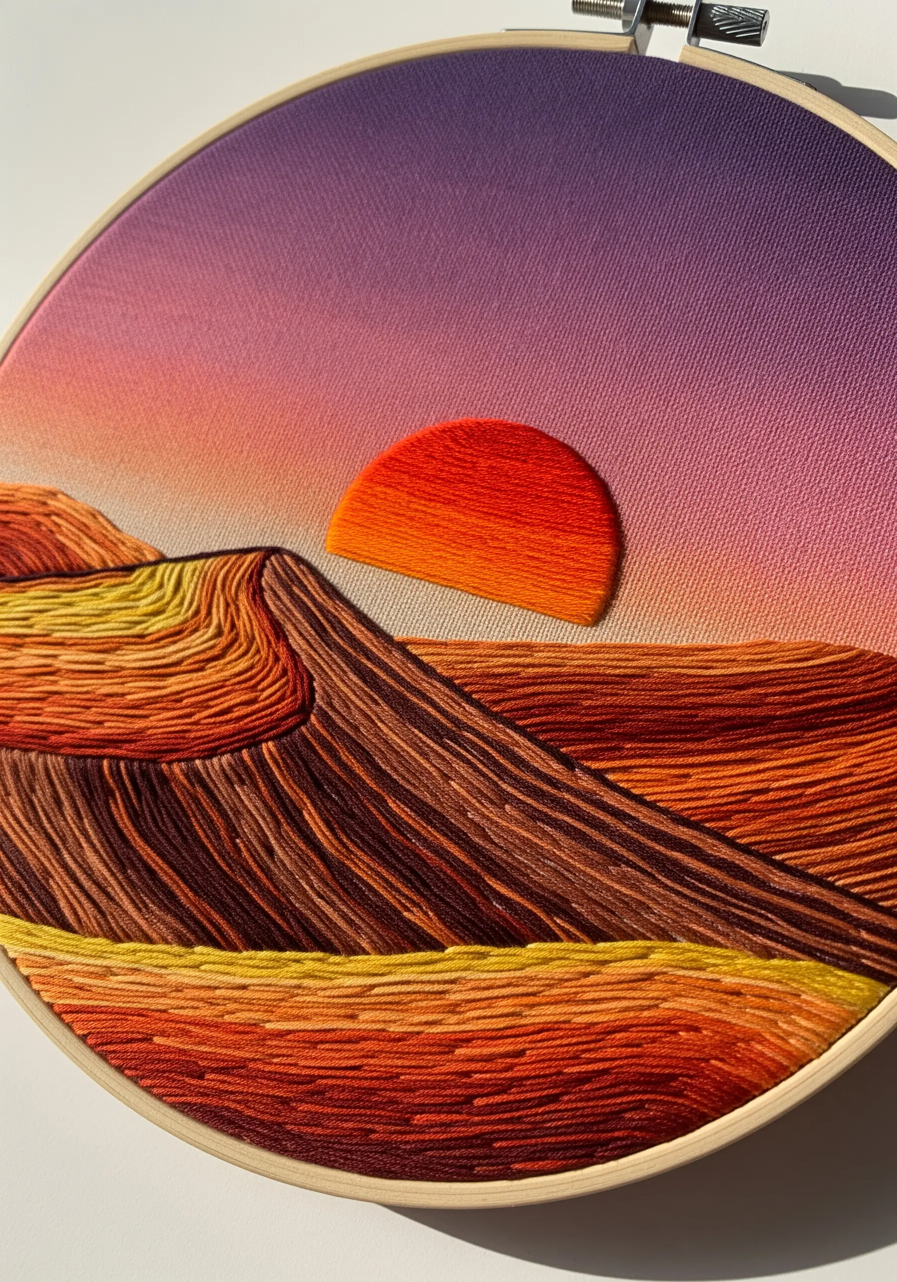 Abstract desert landscape with a satin stitch sun and thread-painted hills in warm sunset colors.