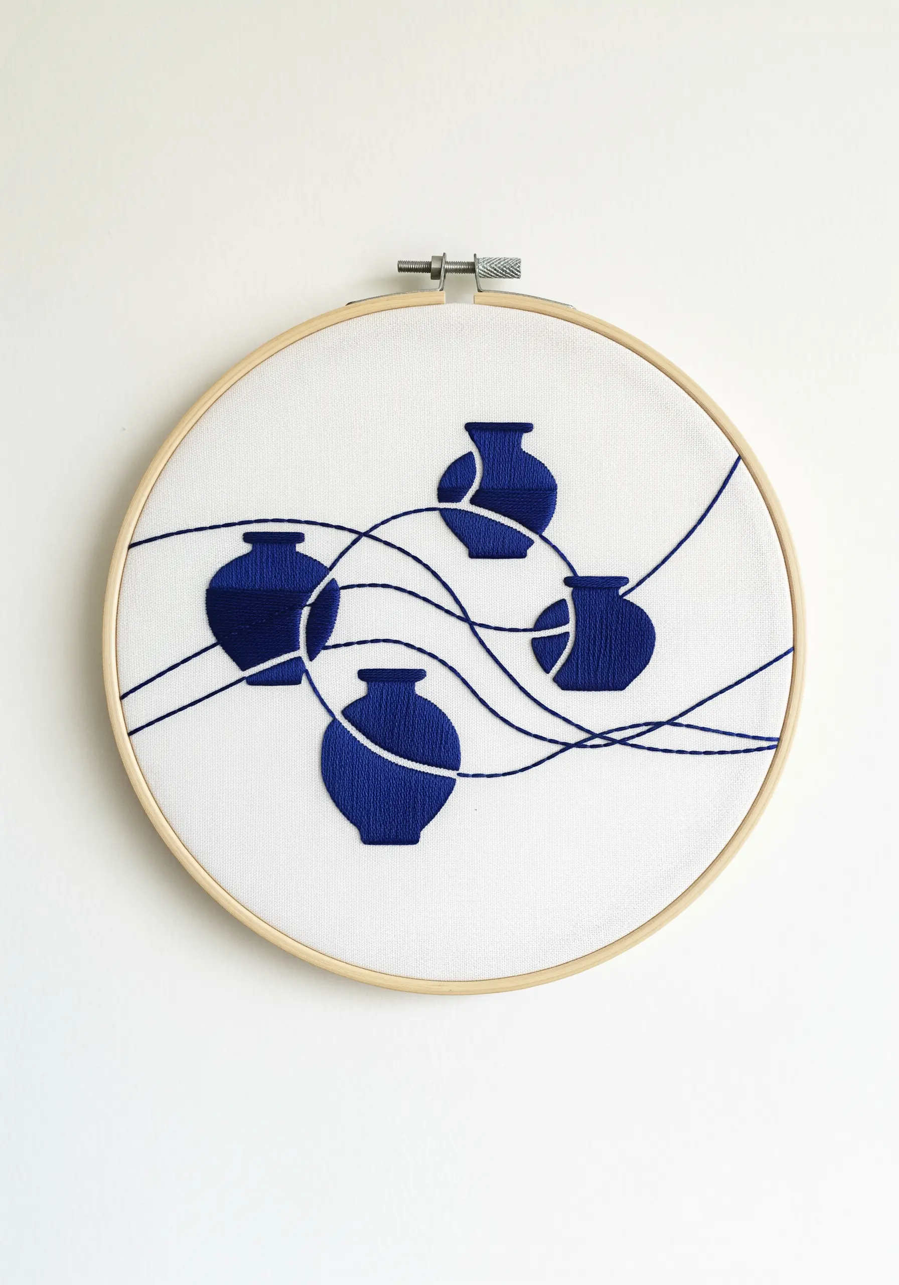 Four blue satin-stitched vases with long, flowing blue lines weaving between them.