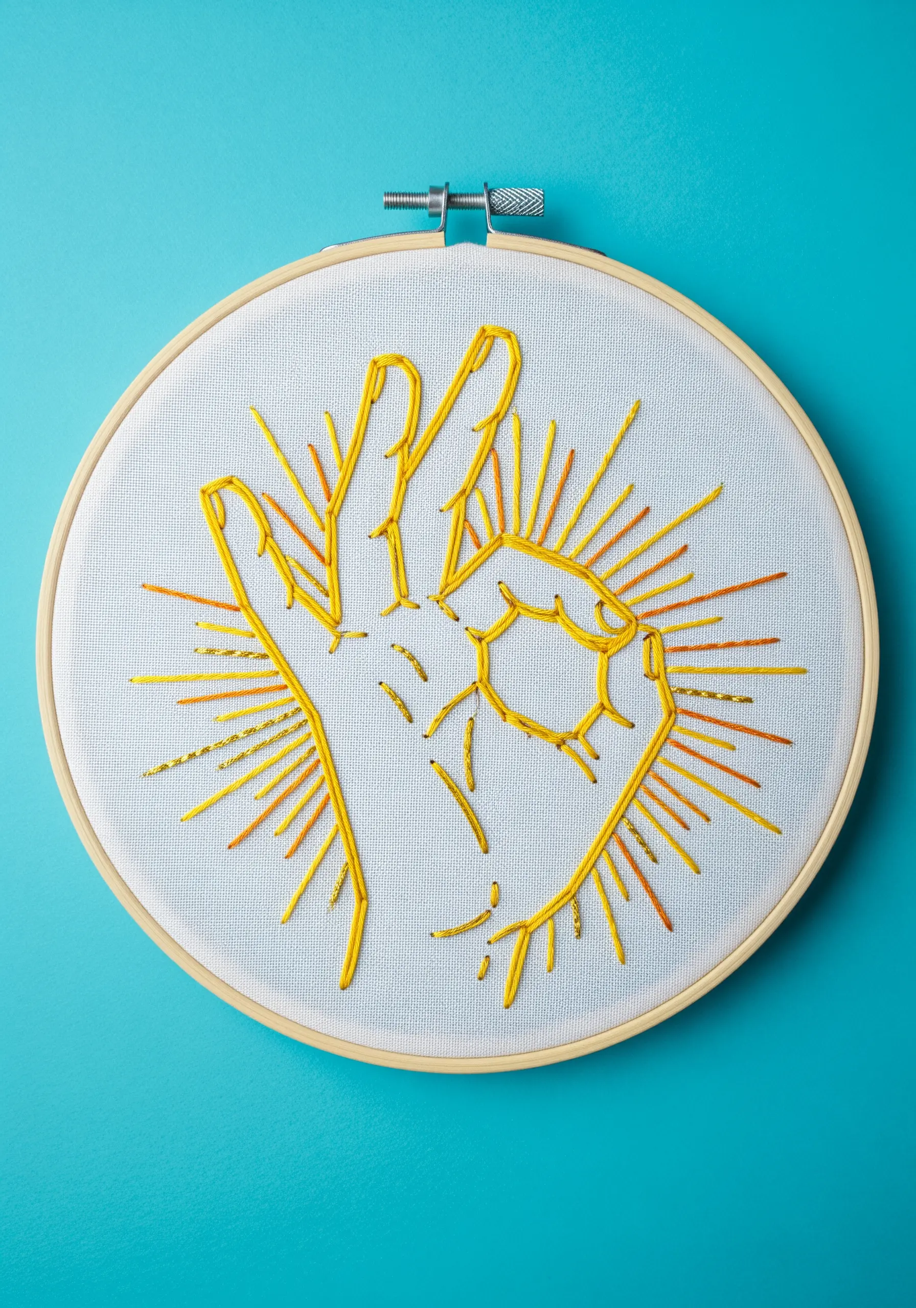 A yellow satin-stitched 'OK' hand gesture with radiating lines in yellow and orange.
