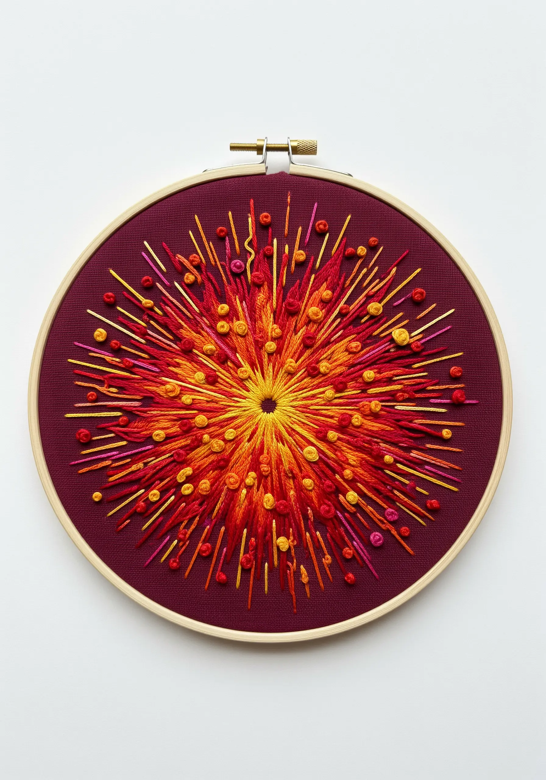 An explosive sunburst embroidery with radiating straight stitches and French knots in warm colors.