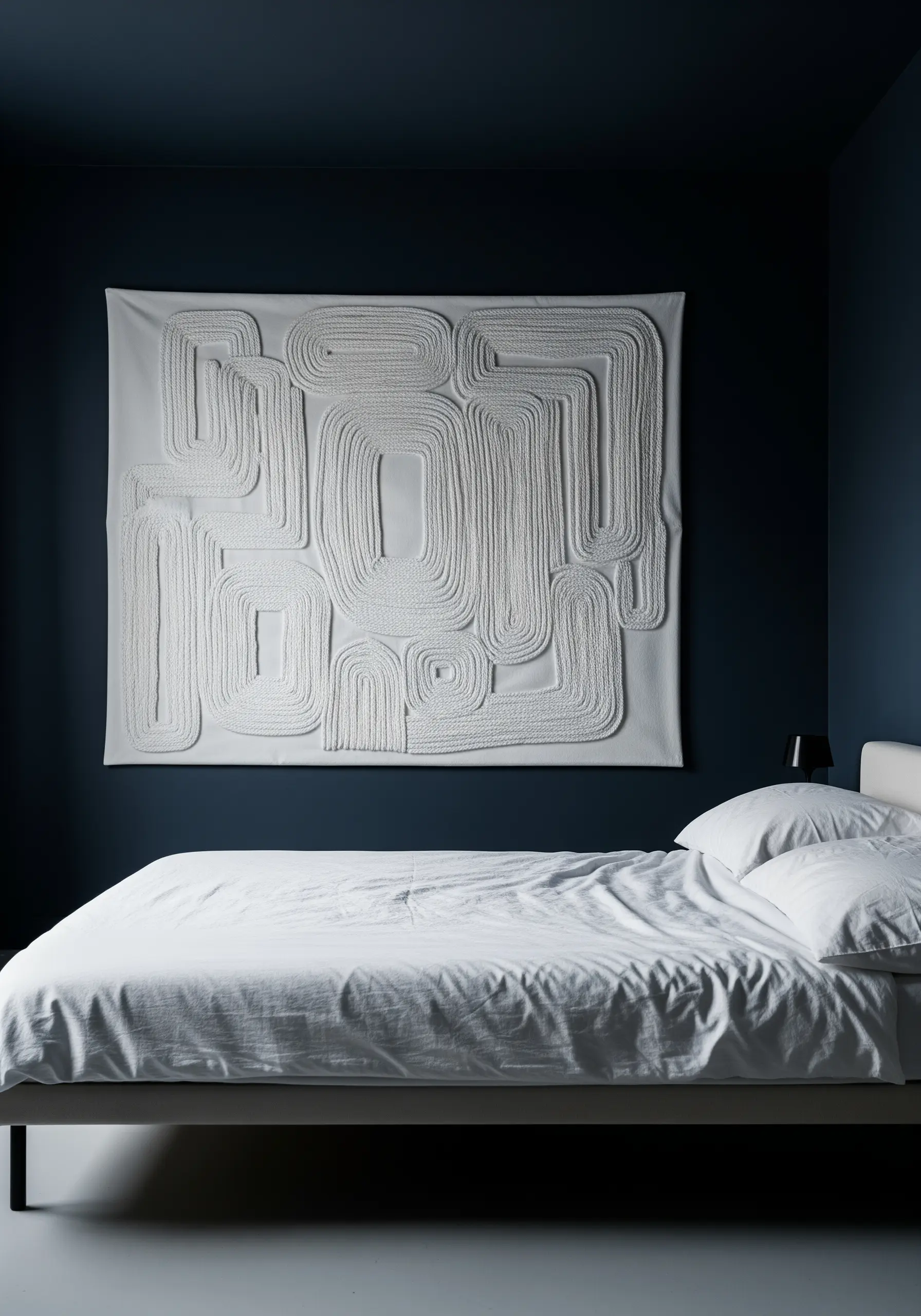 A large white canvas wall hanging with an abstract pattern made from thick, couched white rope.