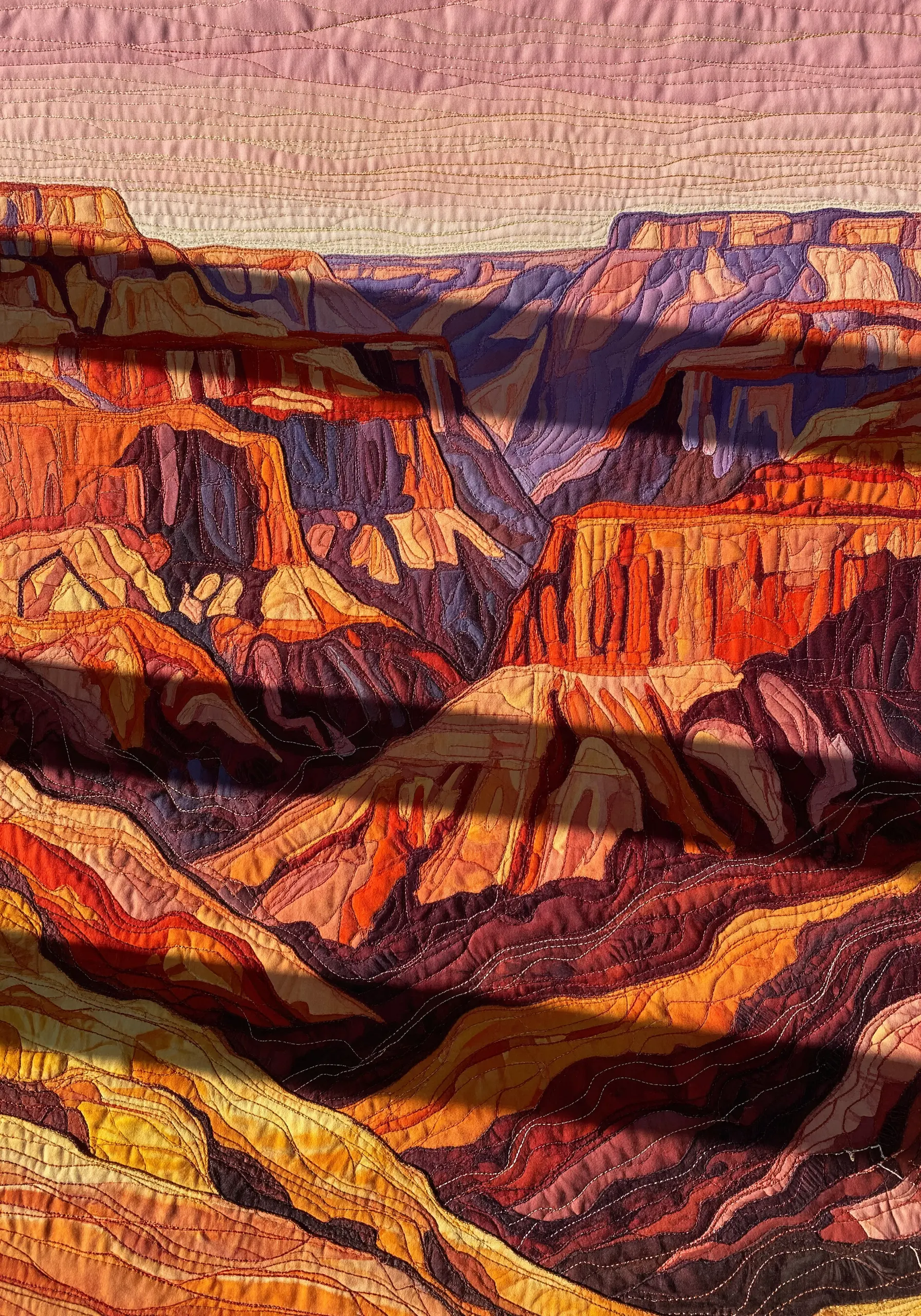 A complex fabric collage of the Grand Canyon using layered textiles and quilting.