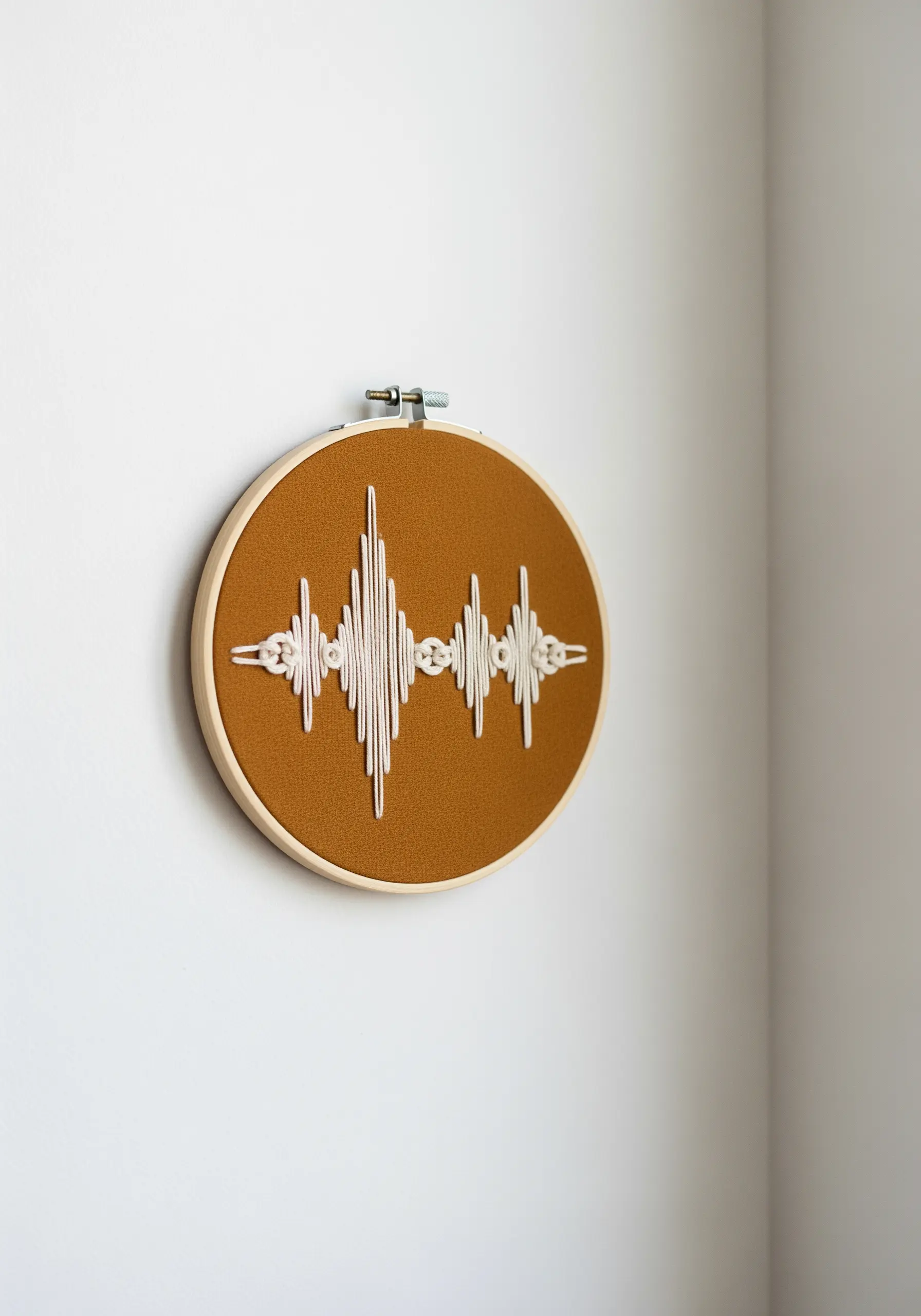 An embroidered soundwave pattern using thick white thread on a mustard-colored fabric.