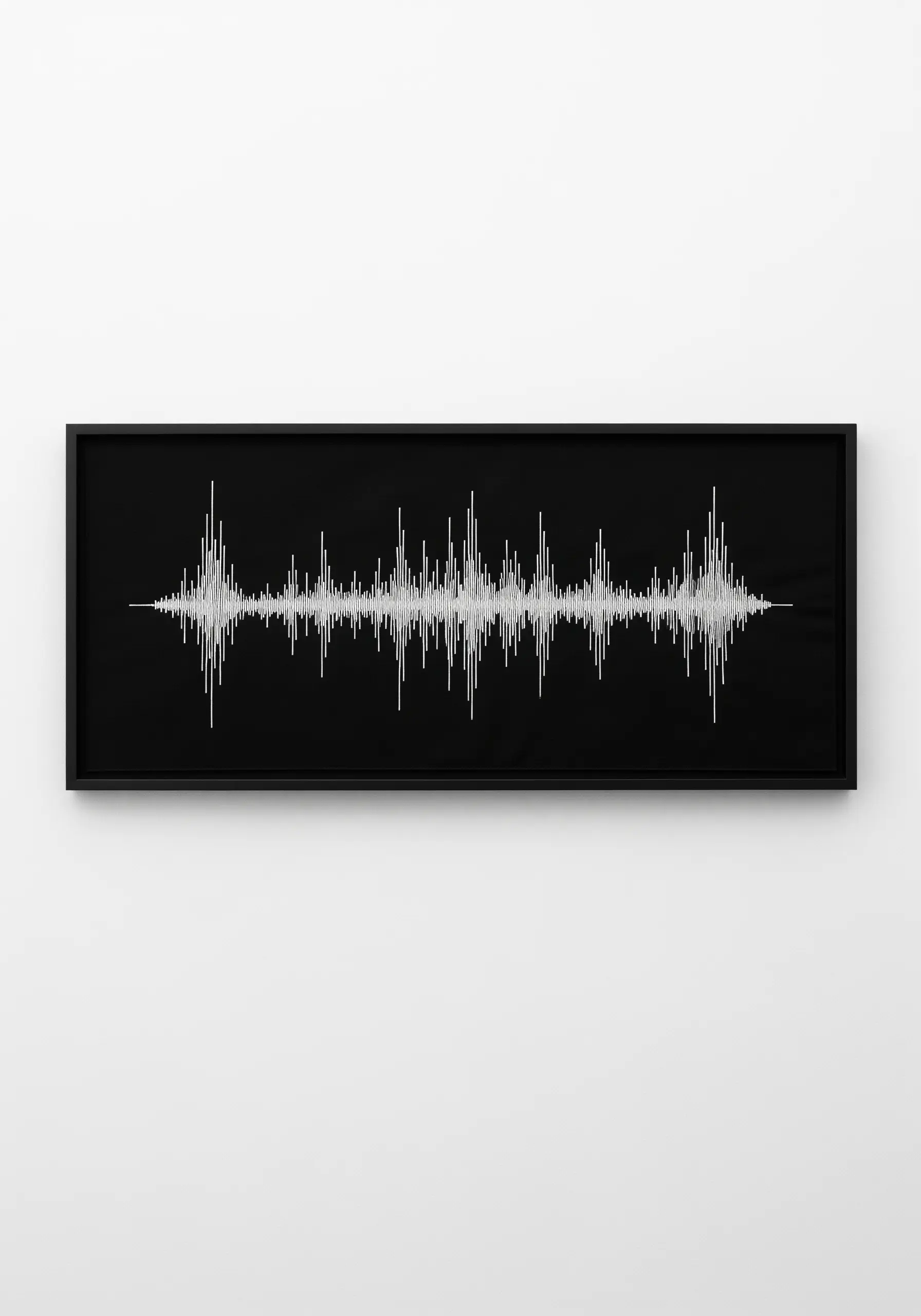 A minimalist white-on-black embroidery of a soundwave, framed horizontally.