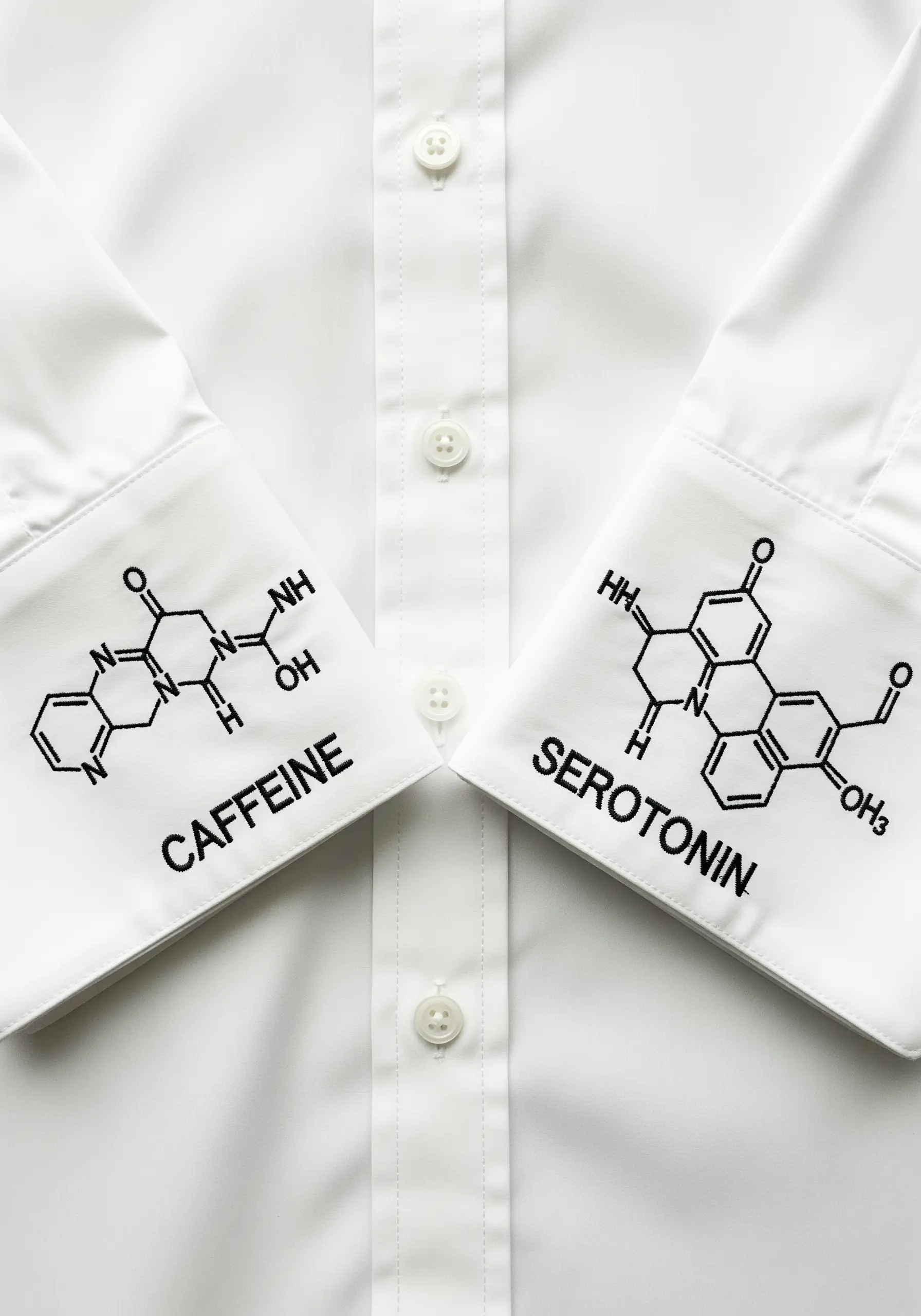 Embroidery of the chemical structures for caffeine and serotonin on the cuffs of a white shirt.