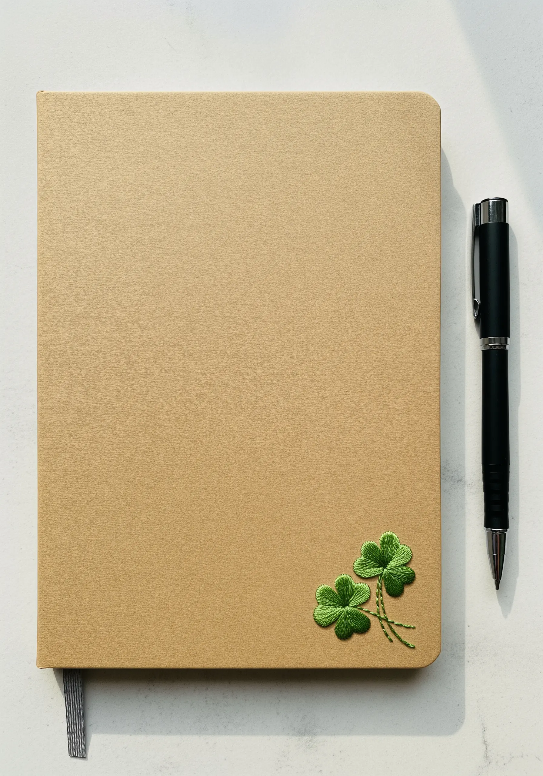 Two small, beautifully shaded four-leaf clovers embroidered on a journal corner.