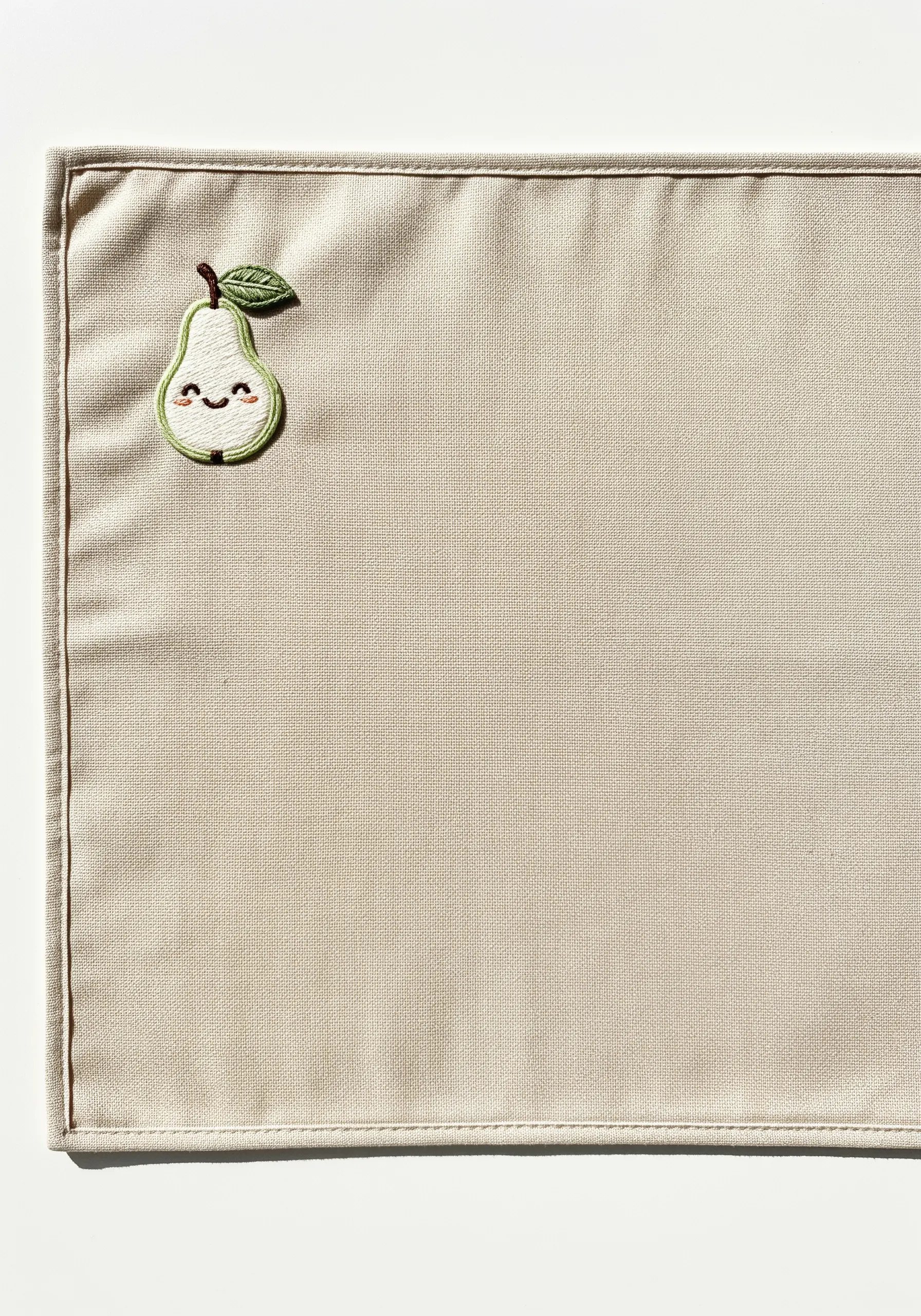 A smiling pear embroidered patch stitched onto the corner of a placemat.