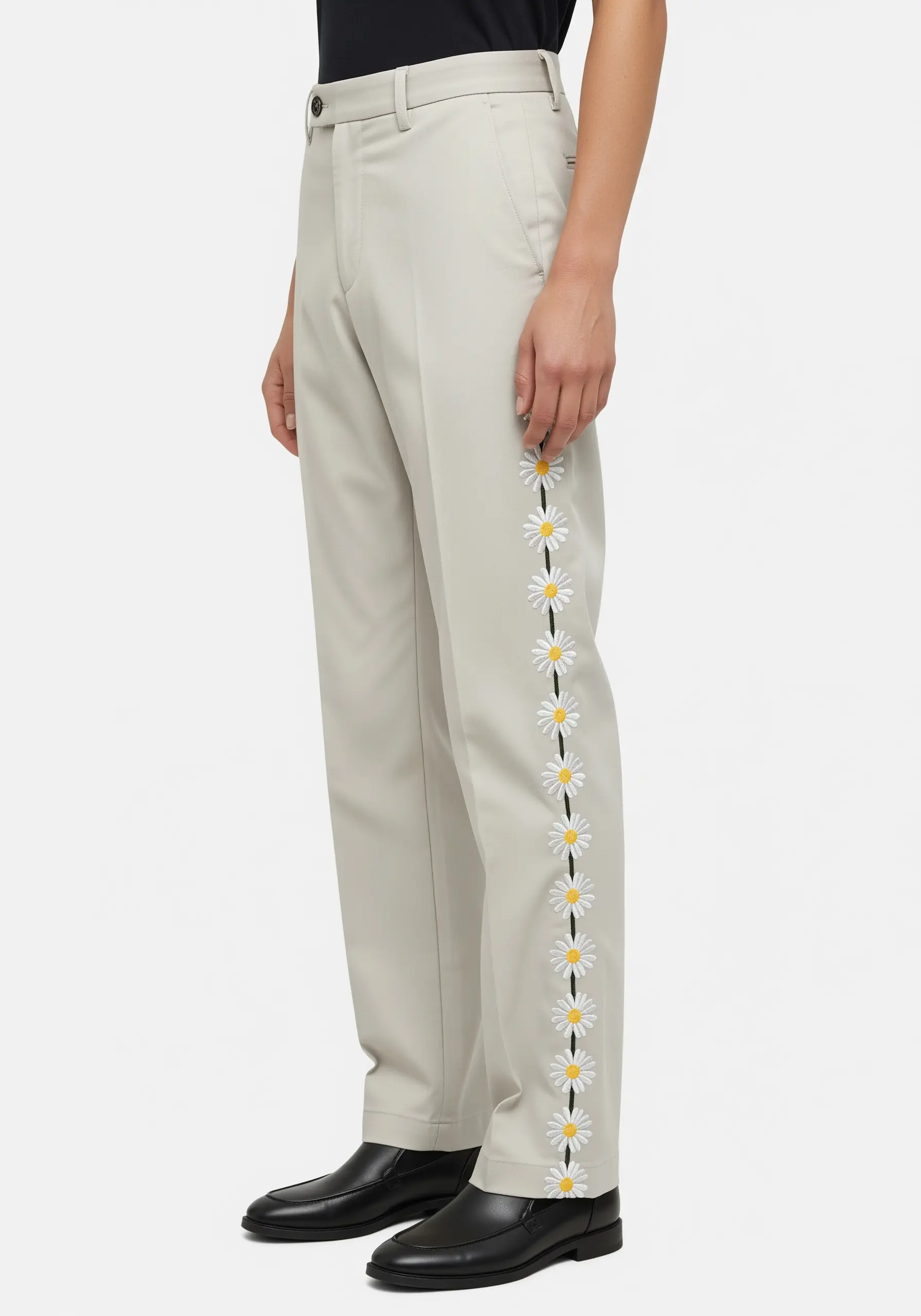 A clean, vertical stripe of embroidered daisies running down the side seam of beige trousers.