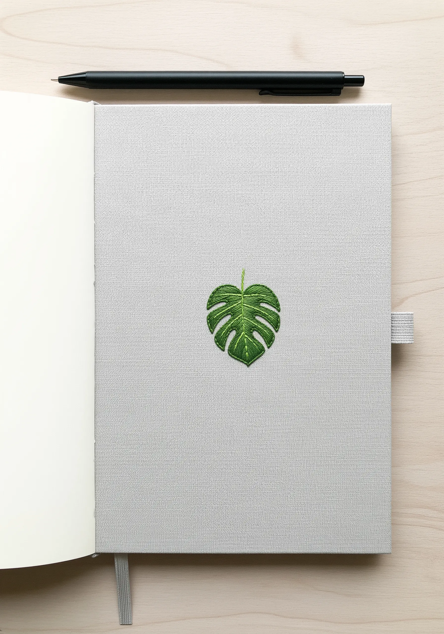 A single, detailed Monstera leaf embroidered in the center of a grey journal.