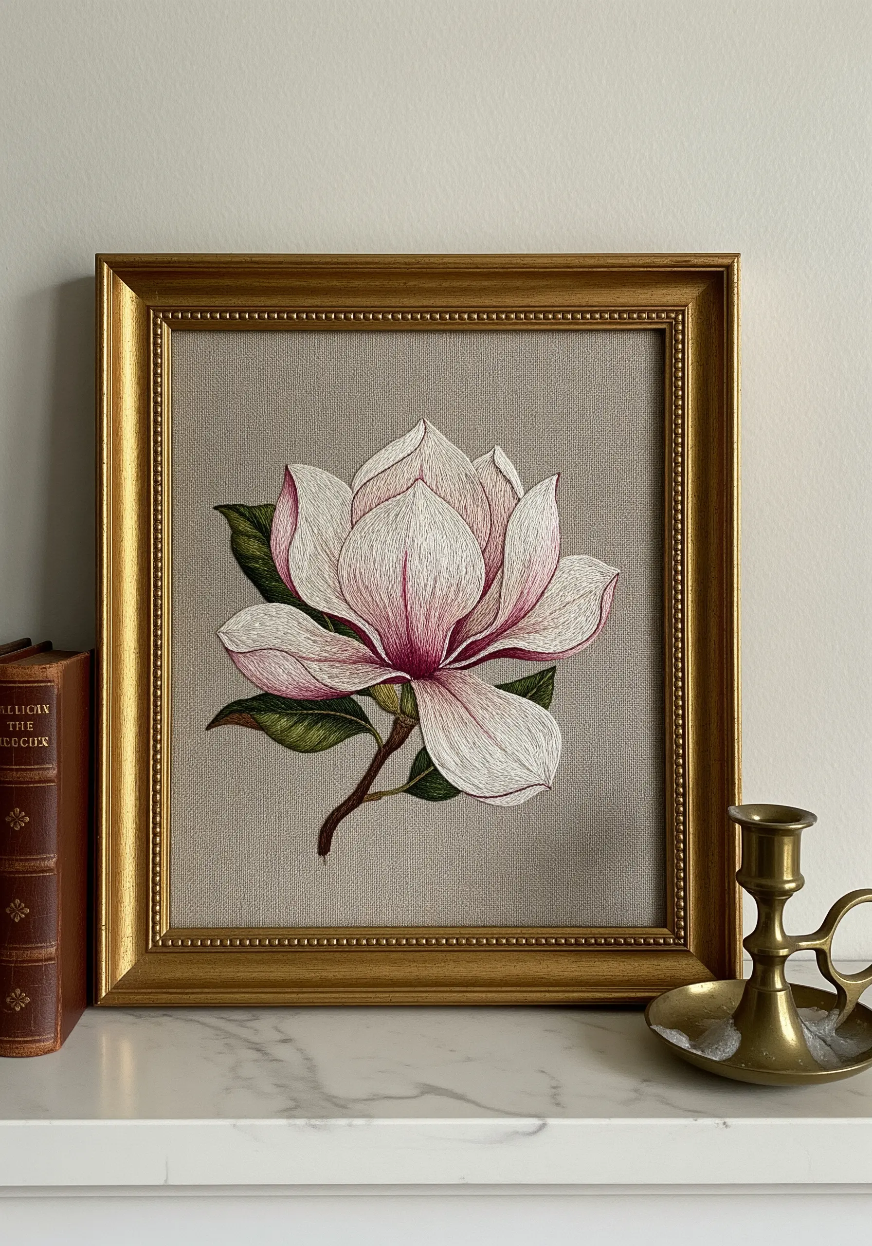 A thread-painted magnolia with pink and white petals, framed in gold.