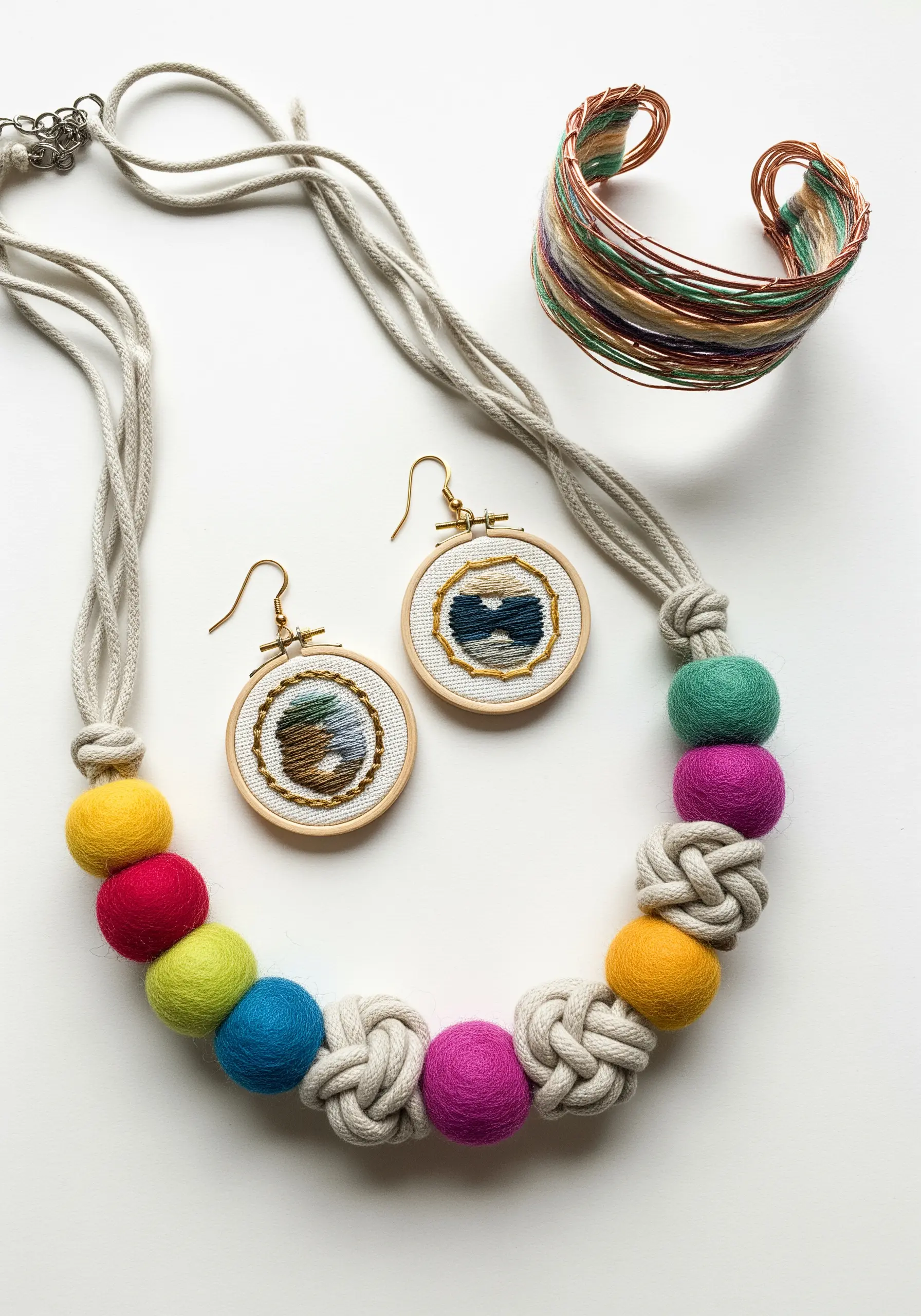 A collection of handmade fiber jewelry including a felt bead necklace and mini hoop earrings.