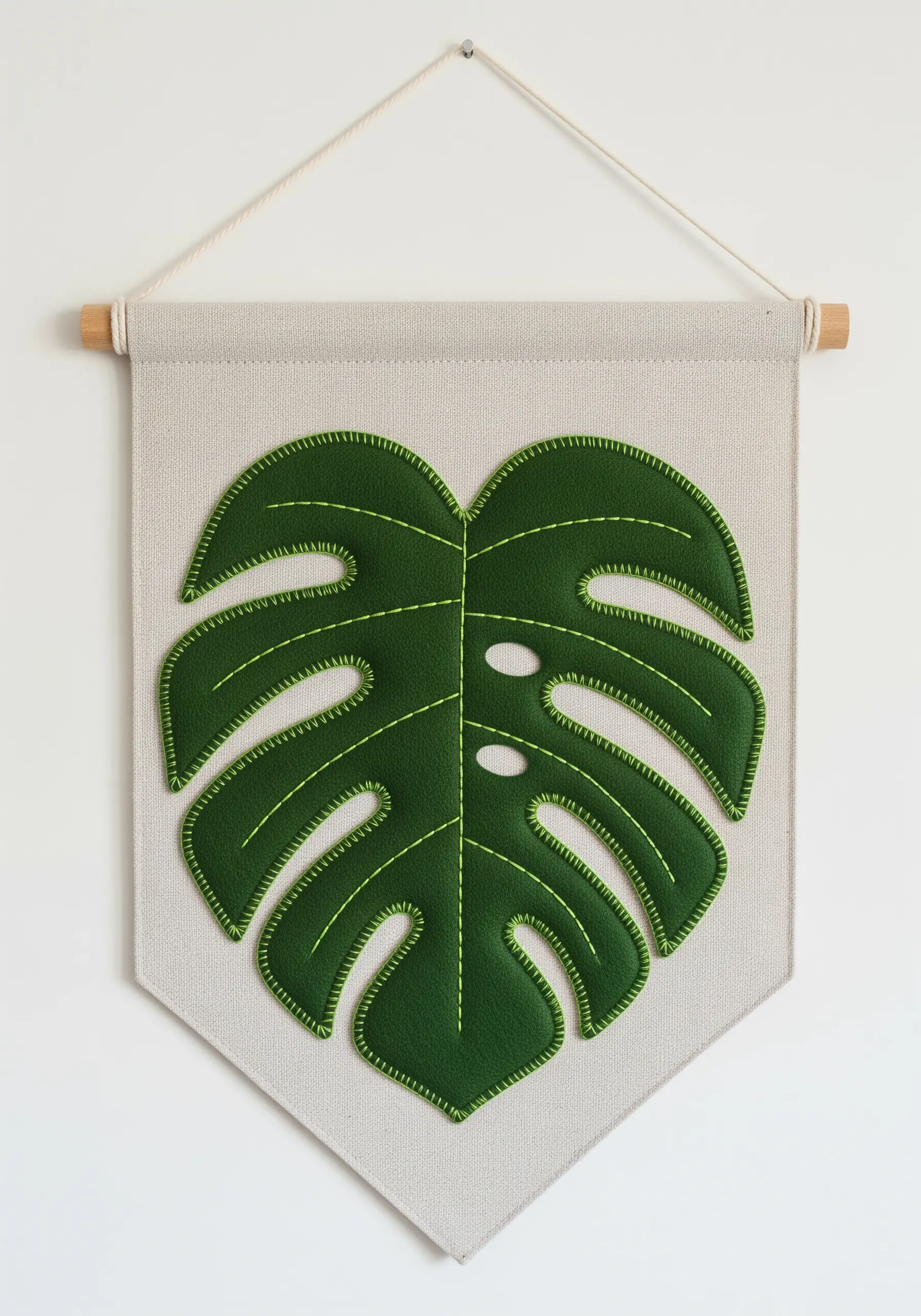 A wall banner with a large green Monstera leaf appliqué stitched with bright green thread.