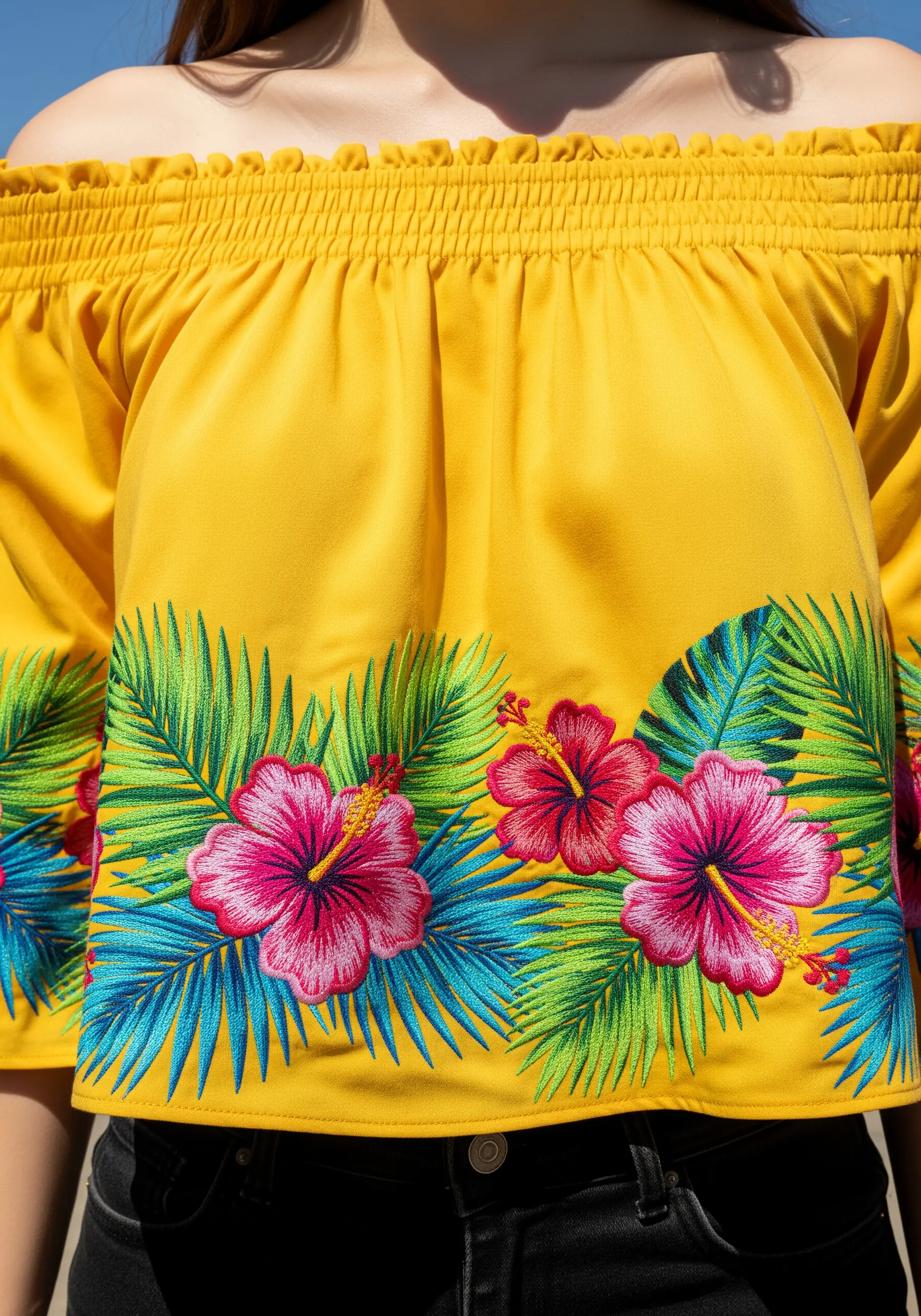 Vibrant tropical hibiscus and palm leaf embroidery on a yellow off-the-shoulder top