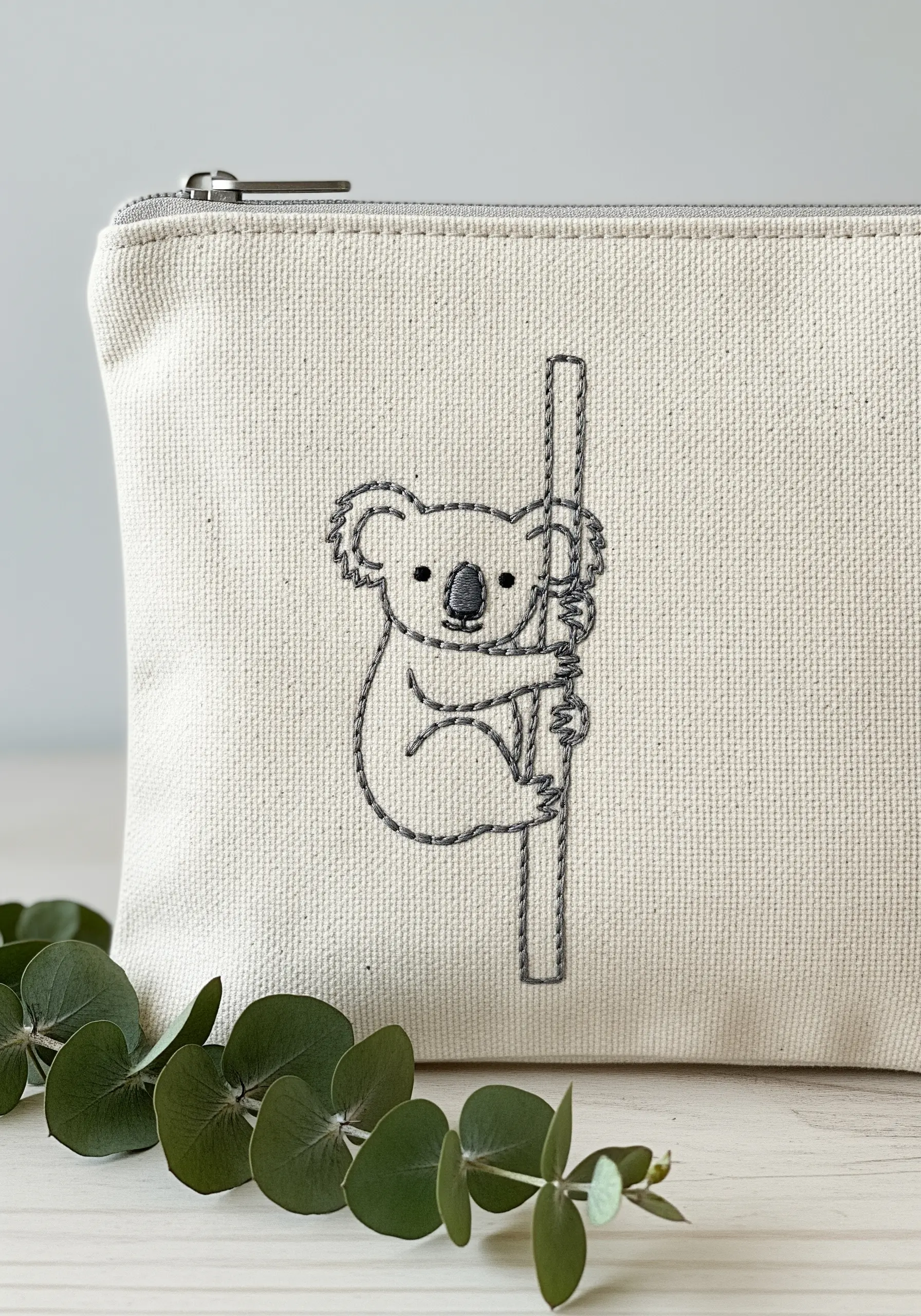 A simple koala embroidered in grey thread on a canvas pouch.