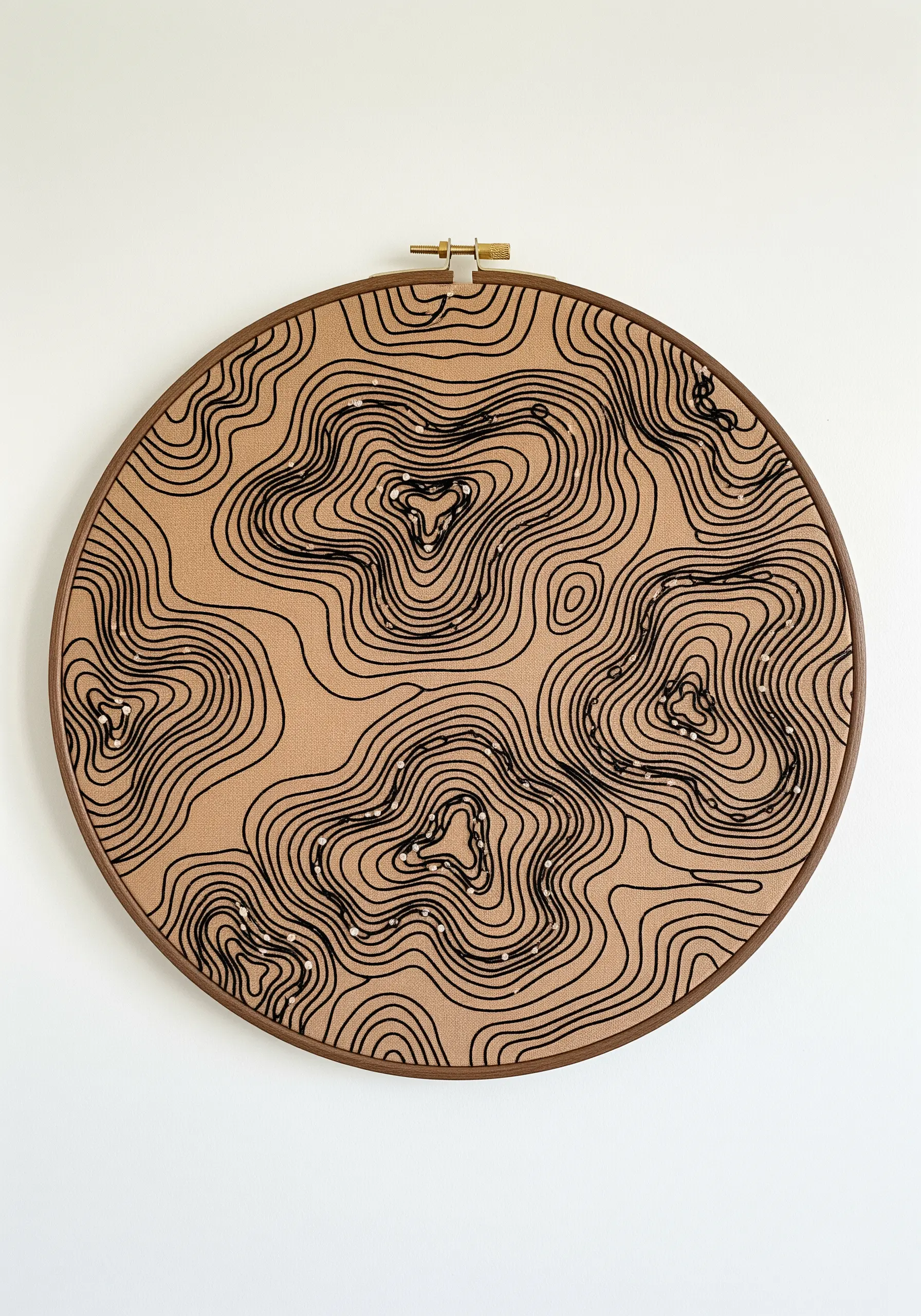 Abstract black topographic line embroidery on tan fabric, accented with tiny white beads.