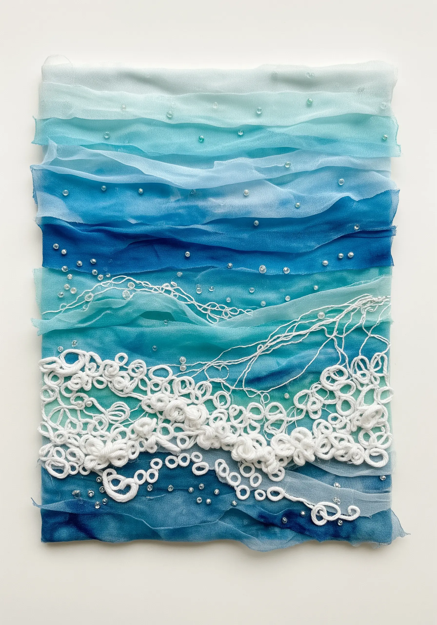 Abstract ocean scene with layered blue sheer fabrics and textured white yarn for foam.
