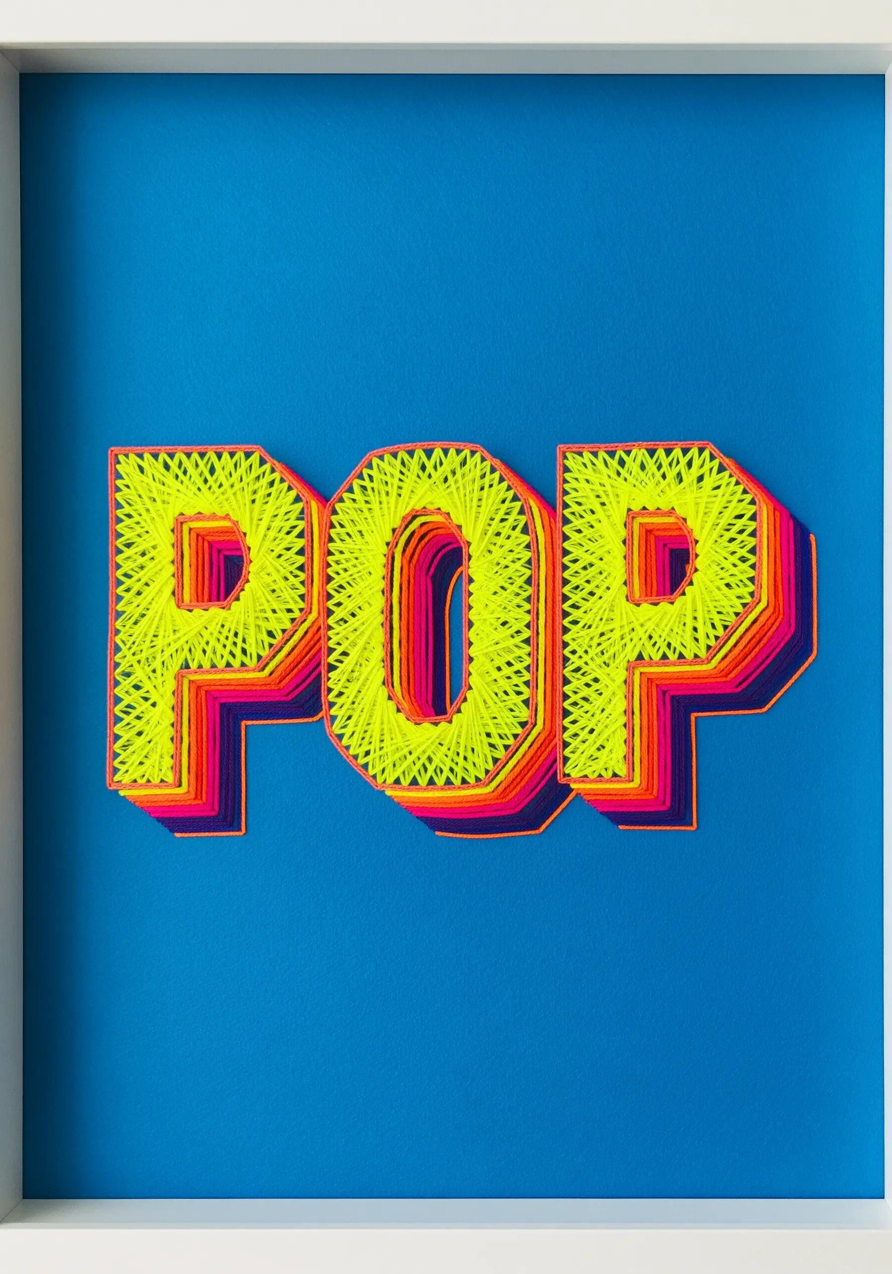 The word POP embroidered in a 3D layered effect with yellow, orange, and pink neon threads.
