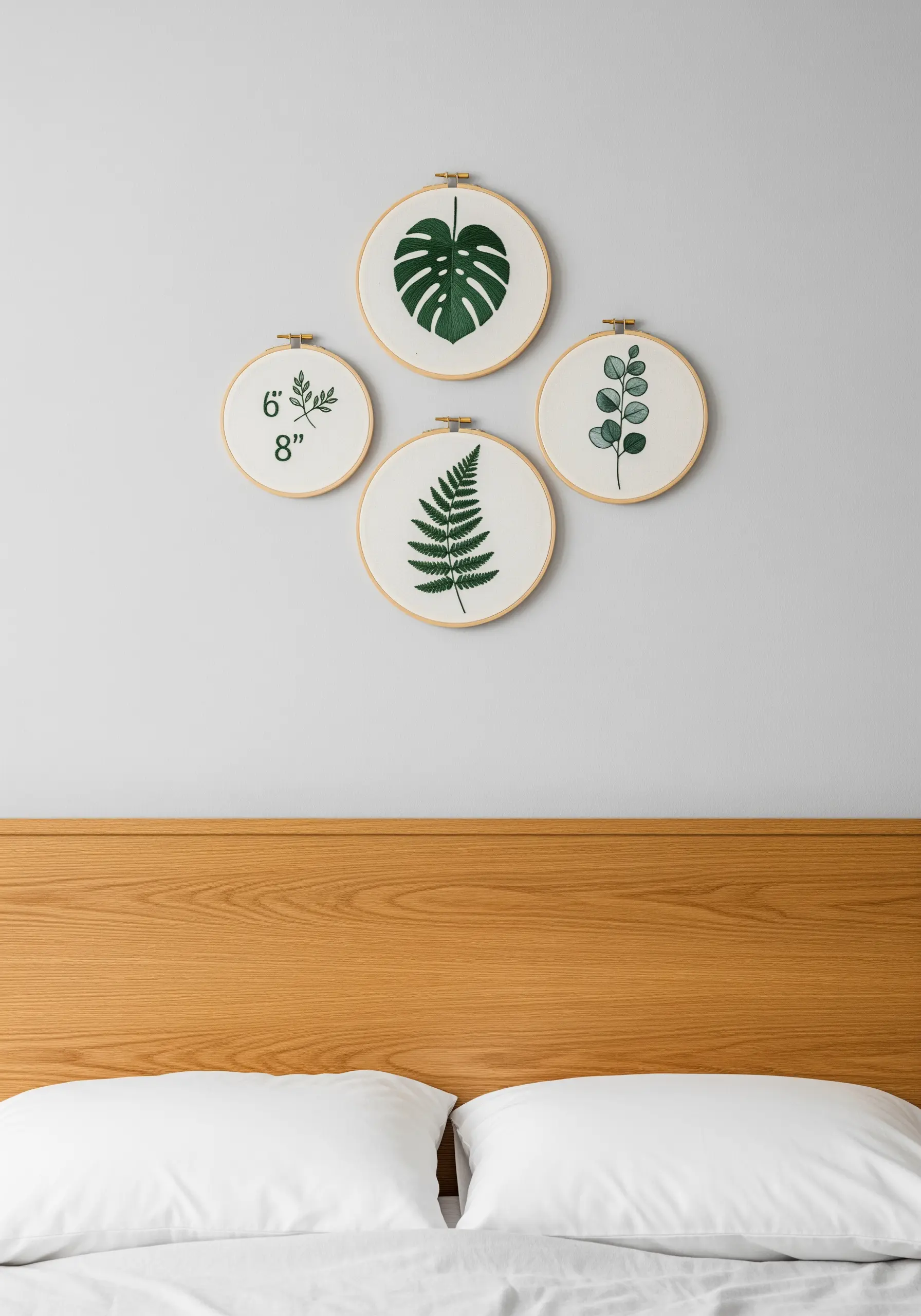 A gallery wall of four embroidery hoops featuring green botanical leaf motifs.