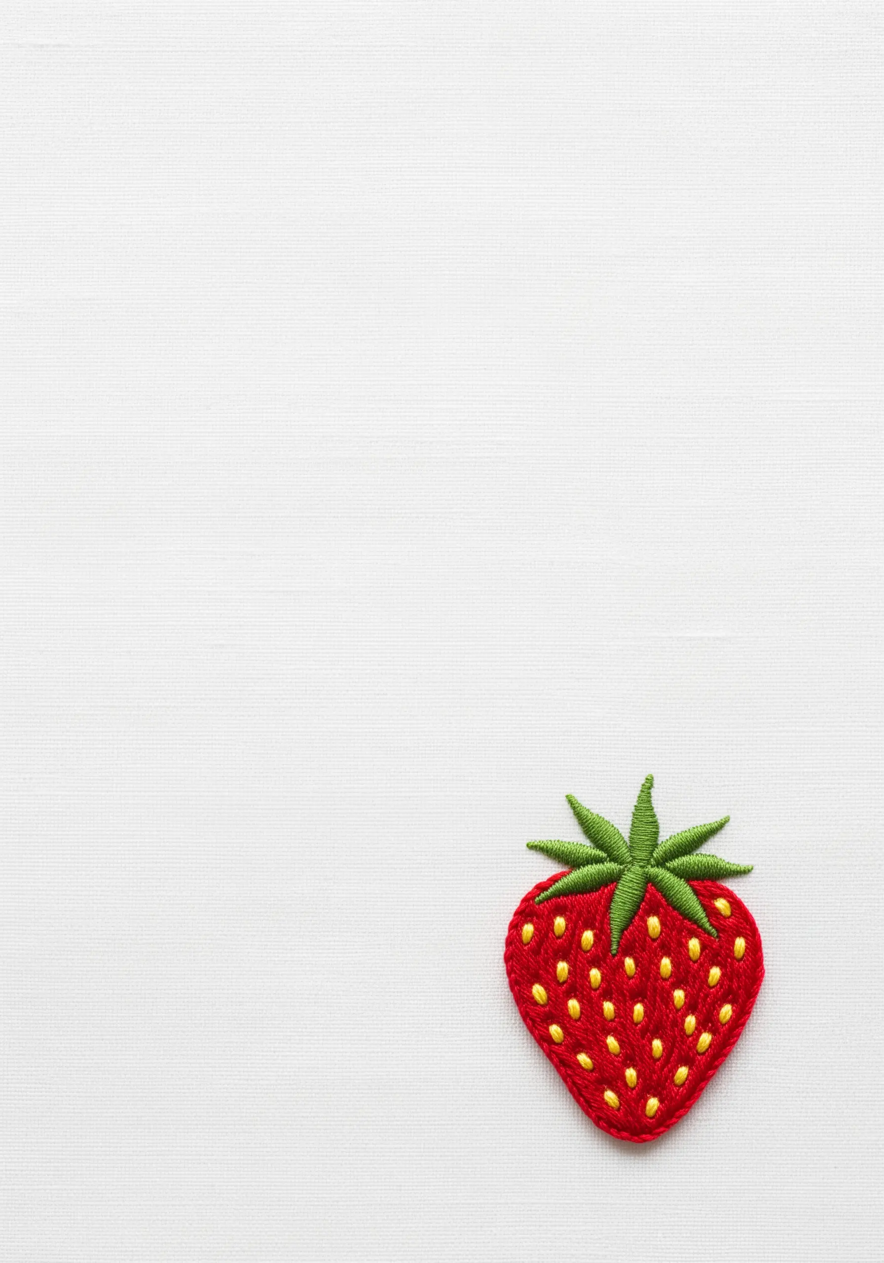 A single embroidered strawberry with red brick stitch and tiny yellow seed stitches.