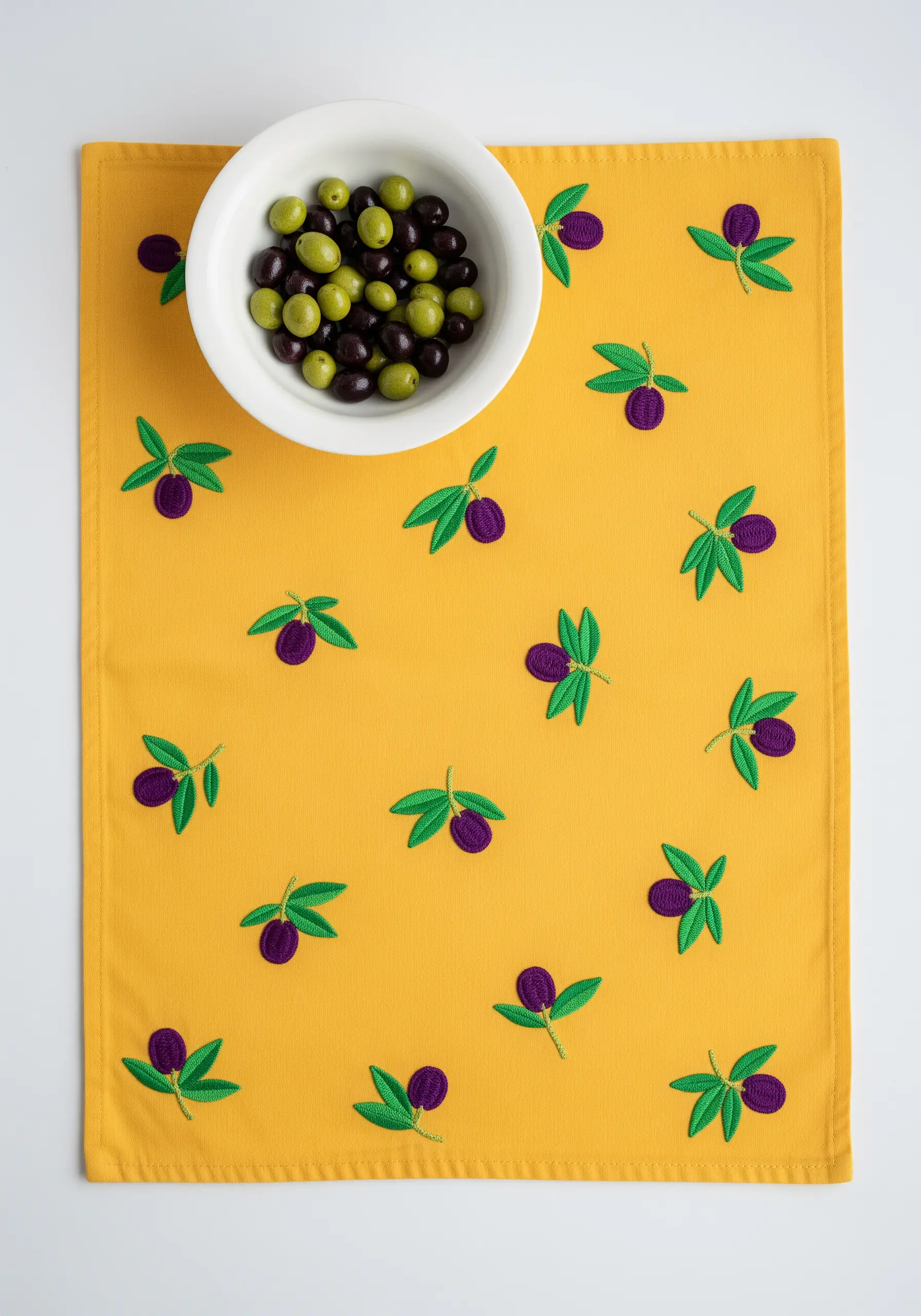 A random pattern of simple embroidered olive sprigs on a bright marigold-yellow placemat.