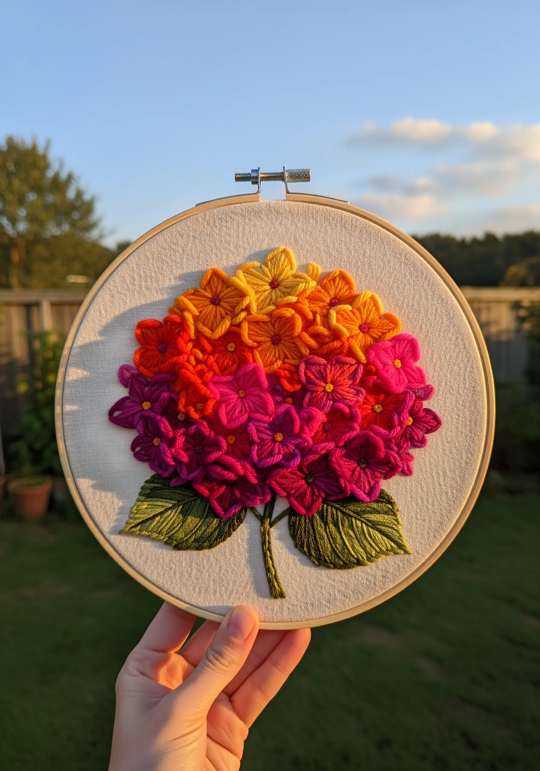 A hydrangea embroidered in a sunset gradient of yellow, orange, pink, and magenta.